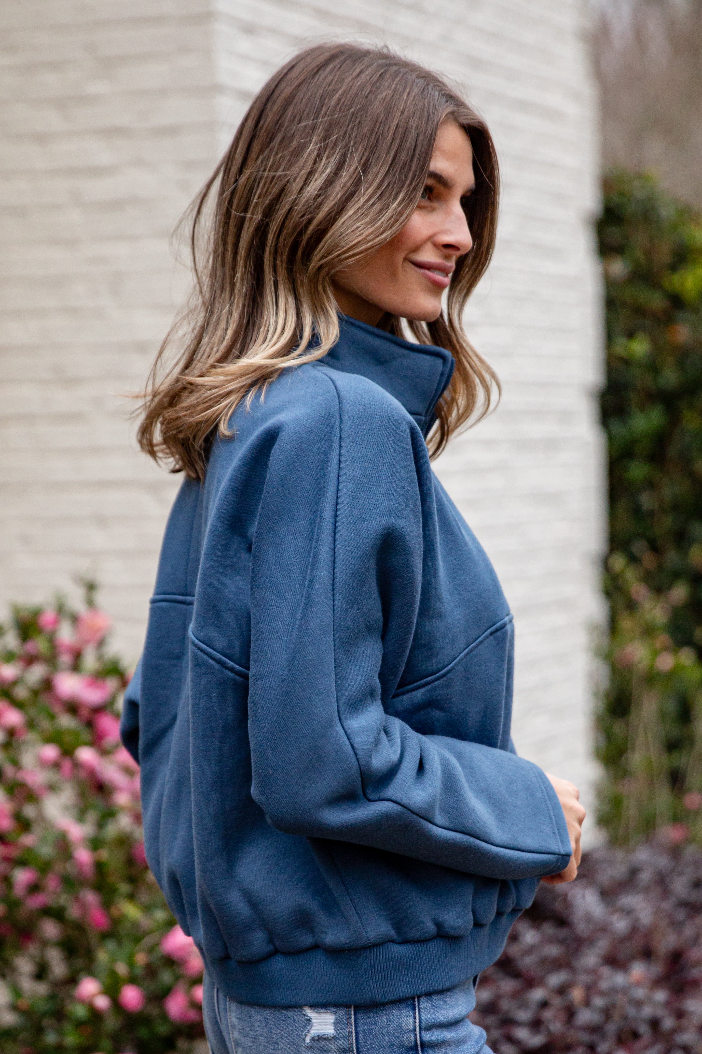 Woman wearing a blue jacket standing outdoors with a blurred background