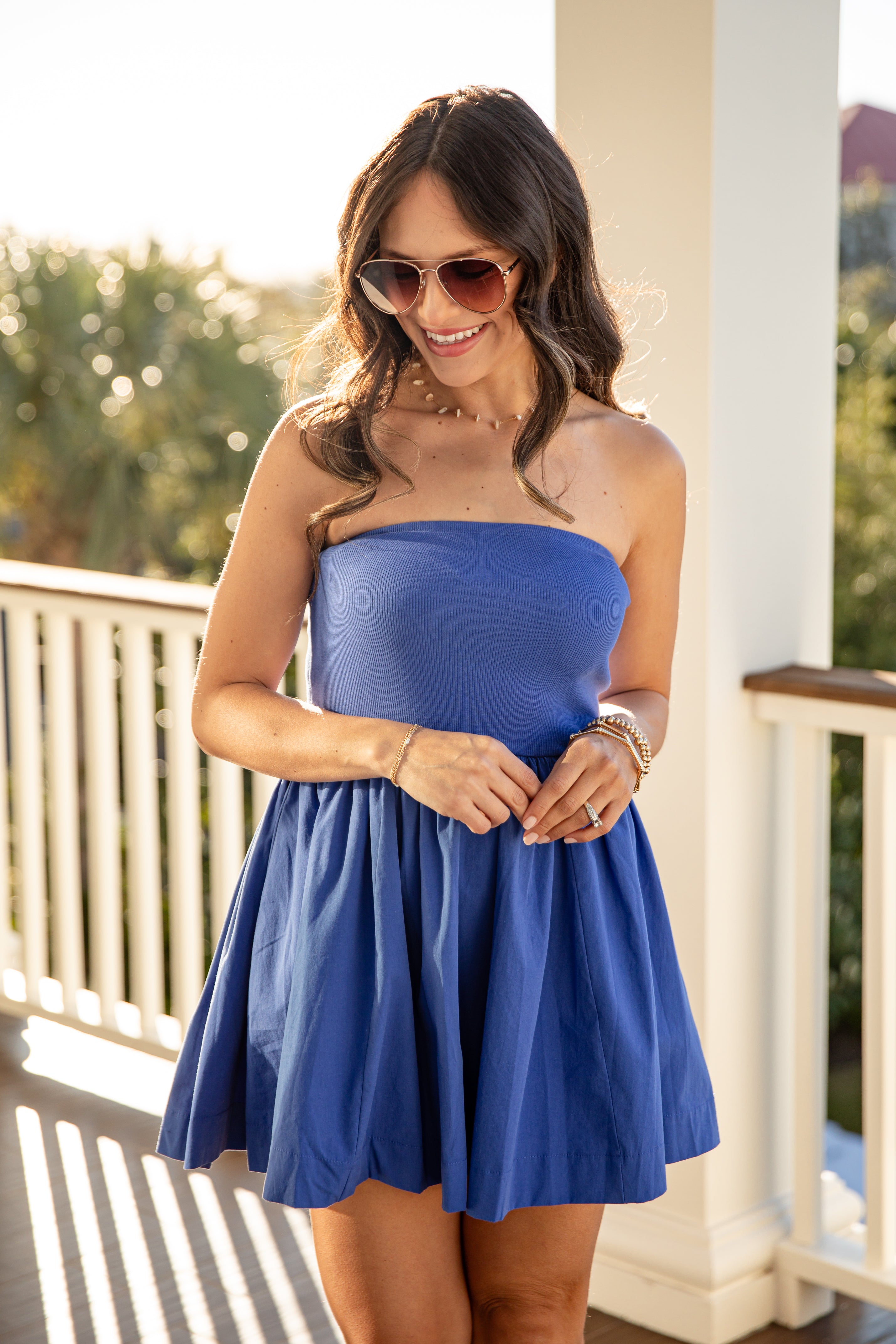 Woman wearing a blue strapless dress on a balcony