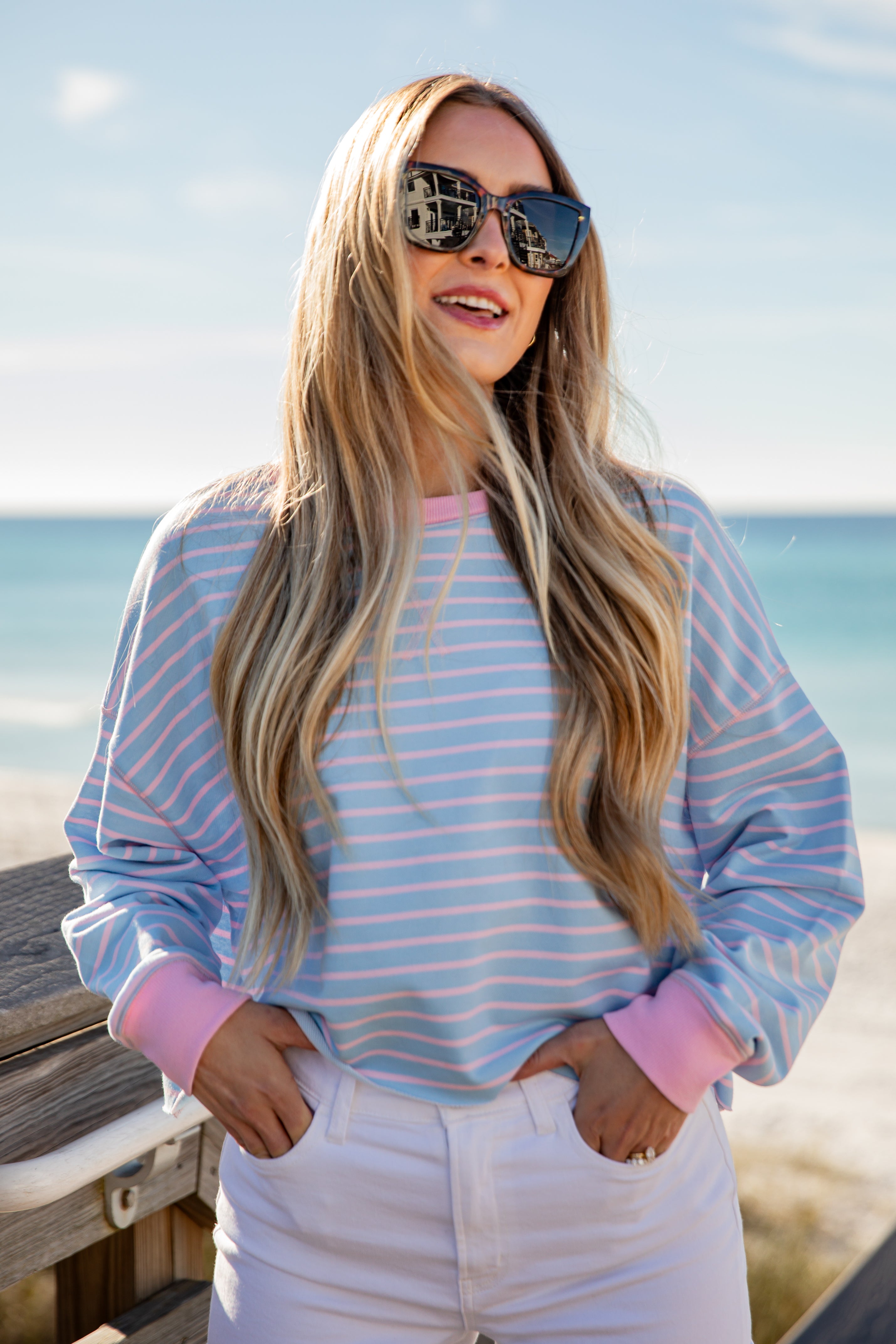 Woman wearing a striped shirt and sunglasses by the beach