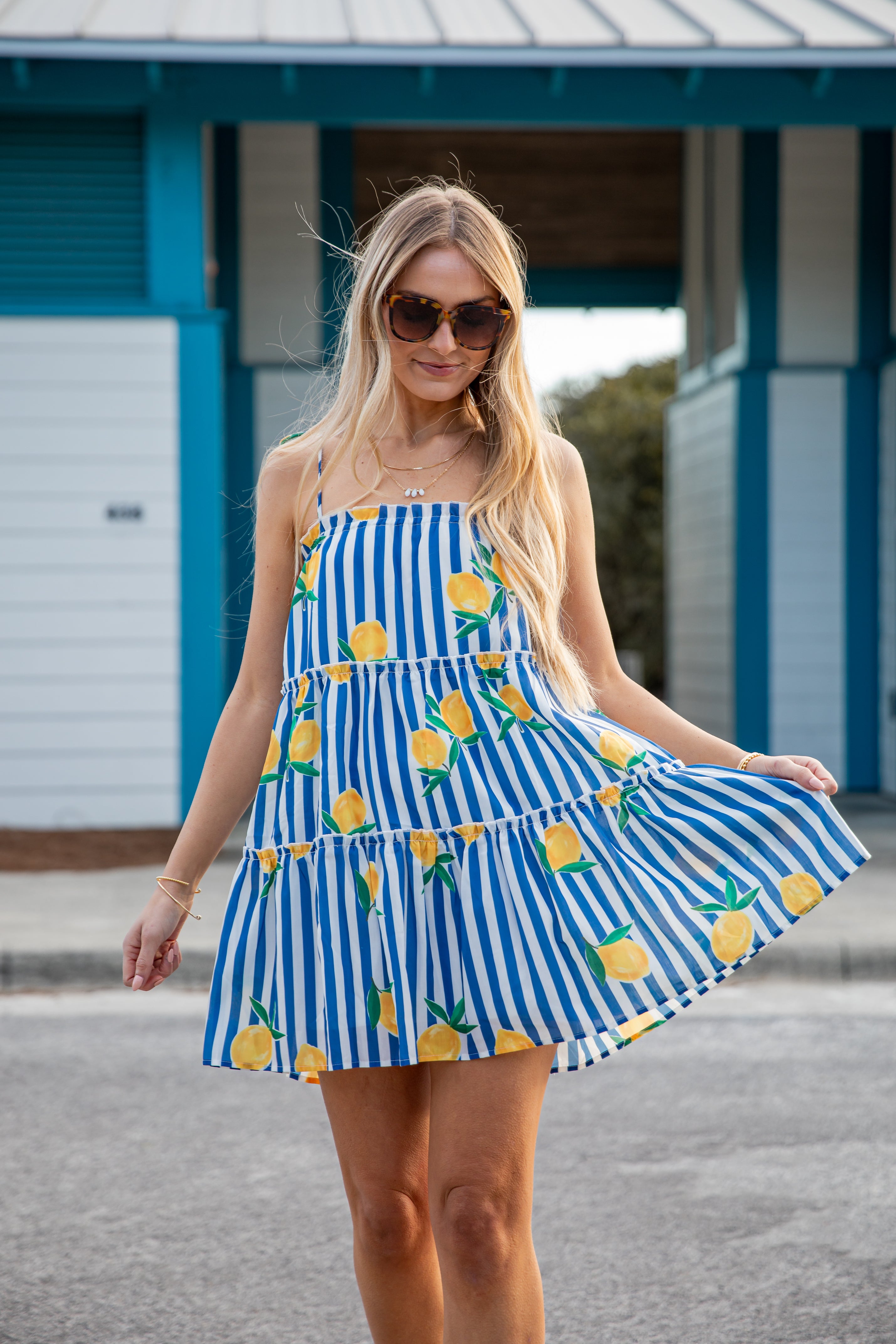 Woman wearing a blue and white striped dress with pineapple patterns outdoors.