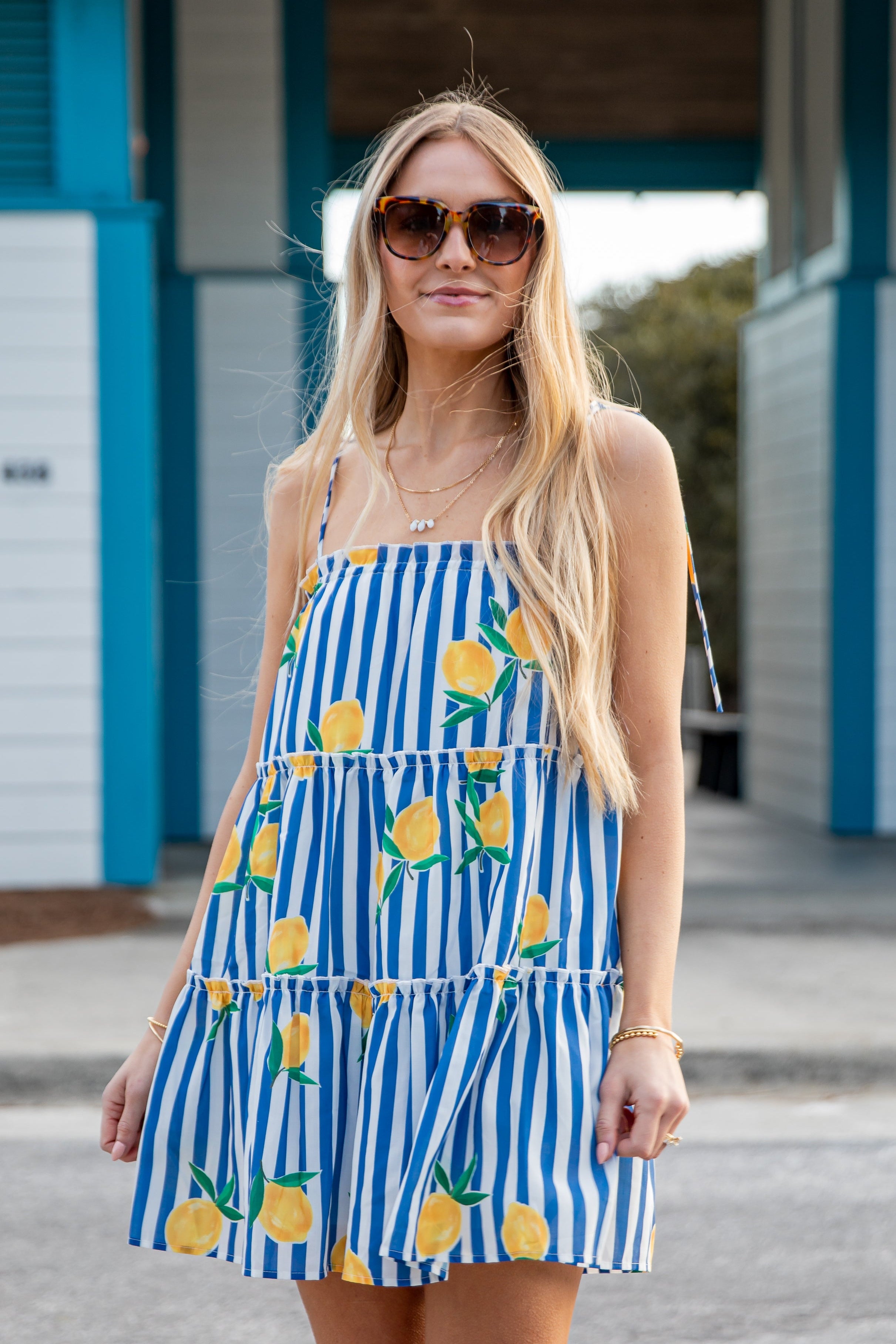 Woman wearing a blue and white striped dress with lemon print outdoors.