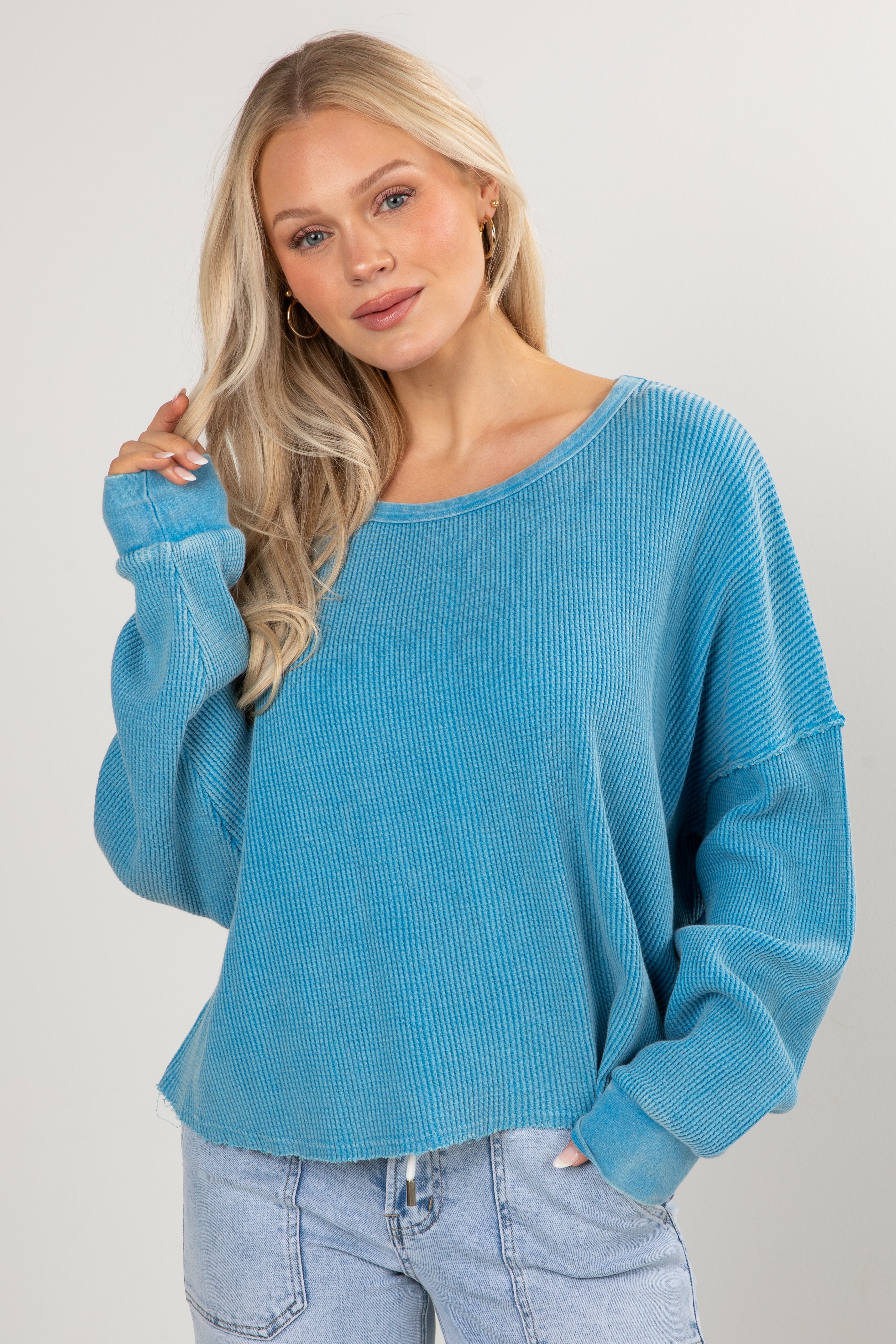 Woman wearing a blue sweater and jeans against a plain background