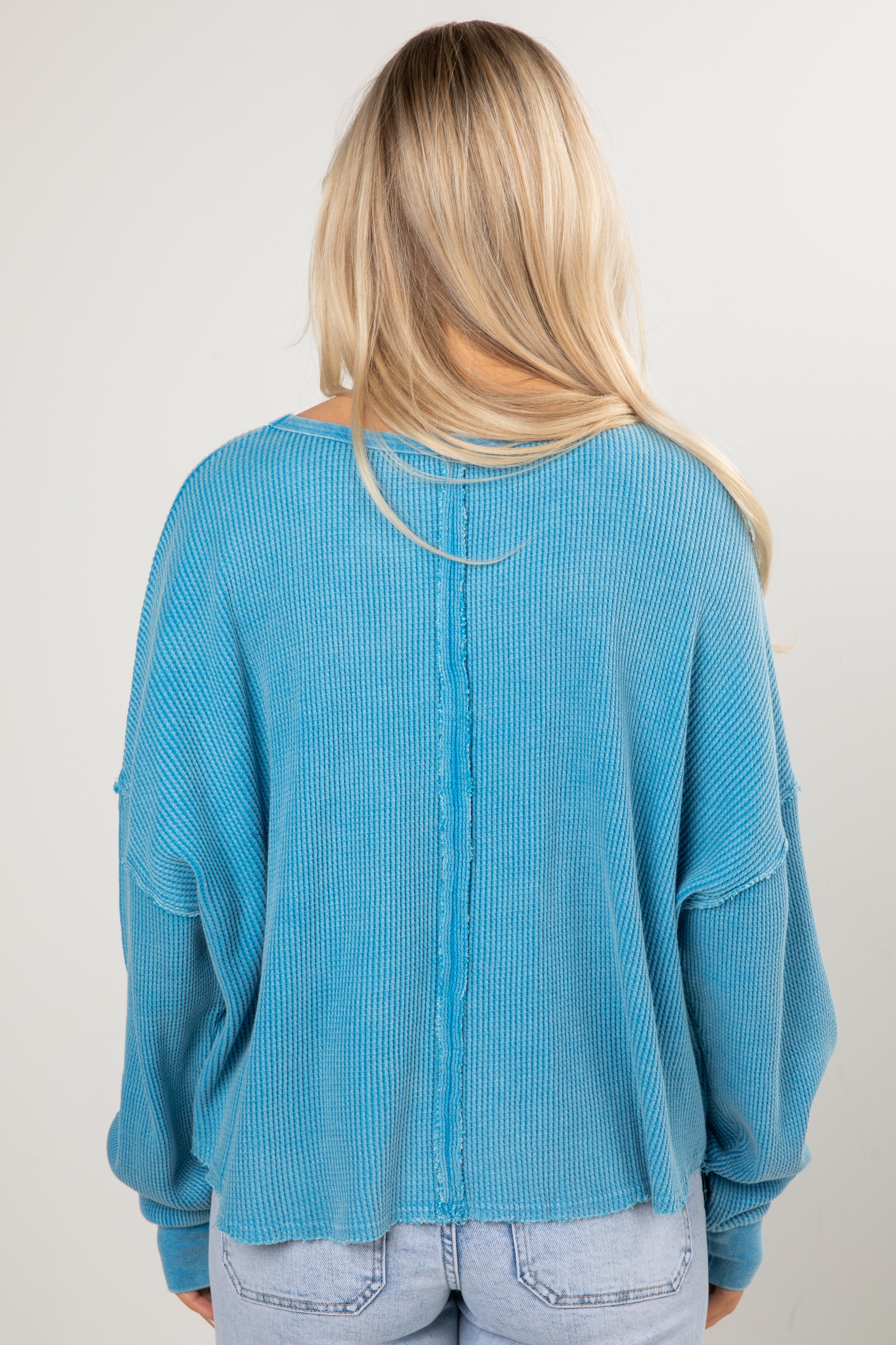 Person wearing a blue sweater from behind on a plain background