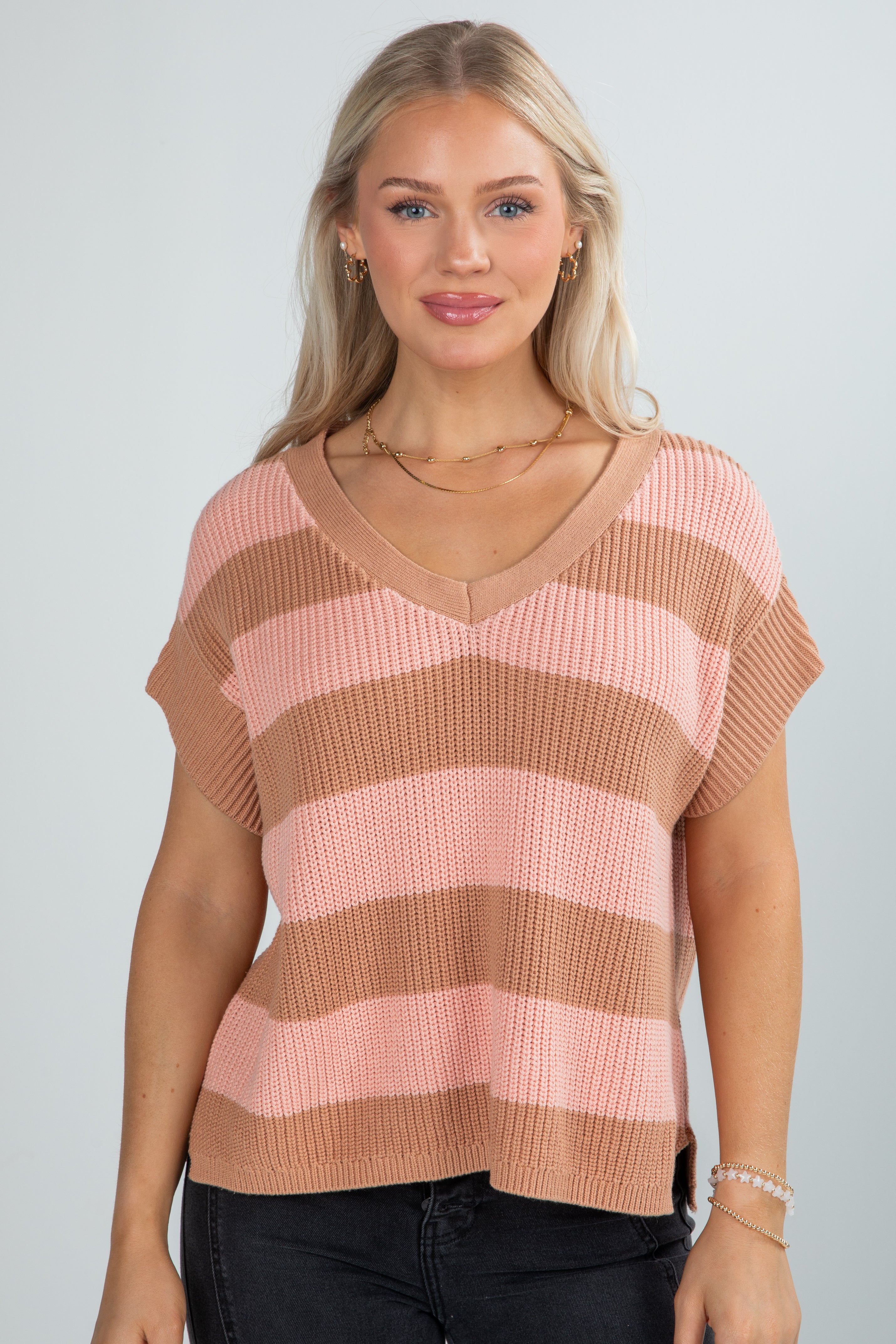 Woman wearing a pink and brown striped sweater against a plain background