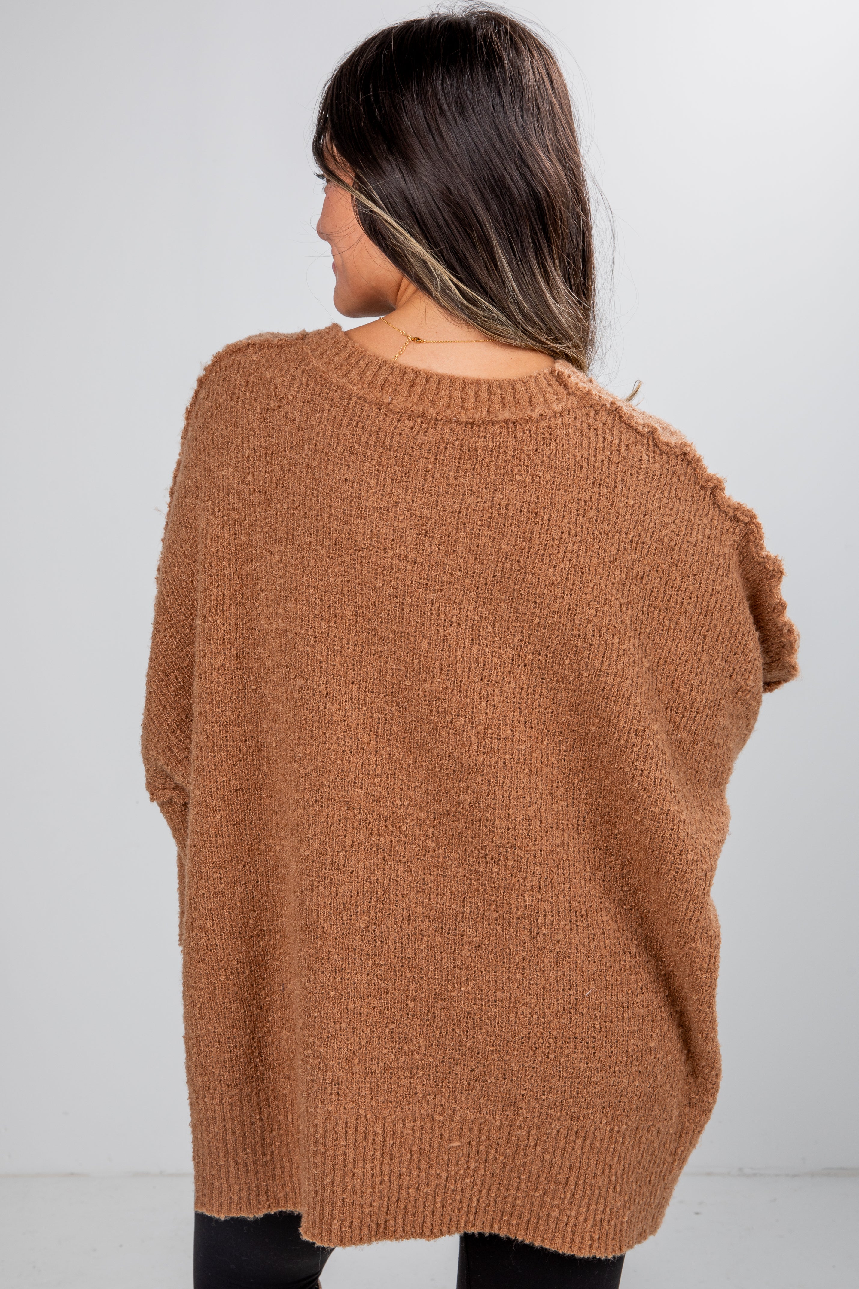 Person wearing a brown sweater from behind on a white background