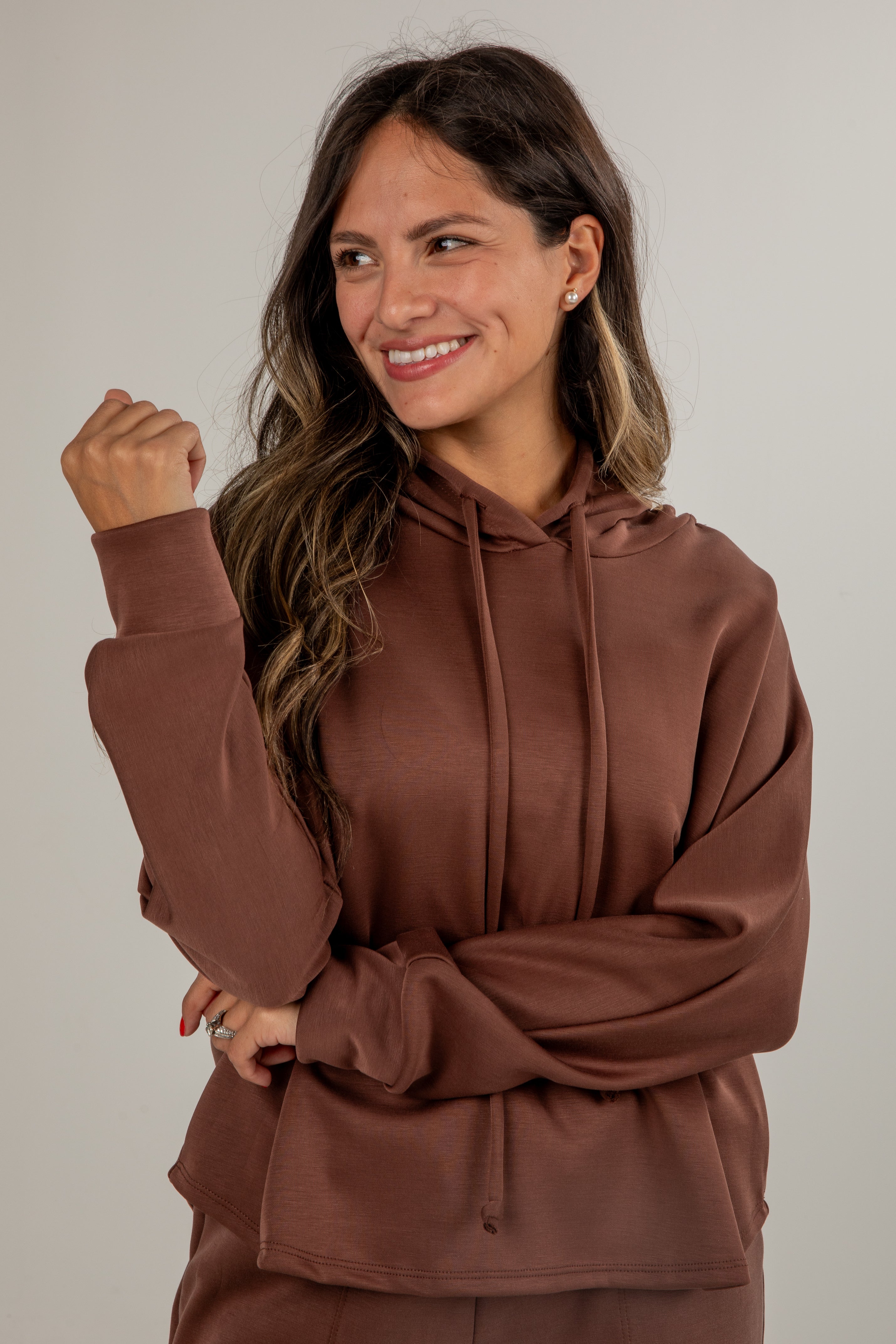 Woman wearing a brown hoodie against a plain background