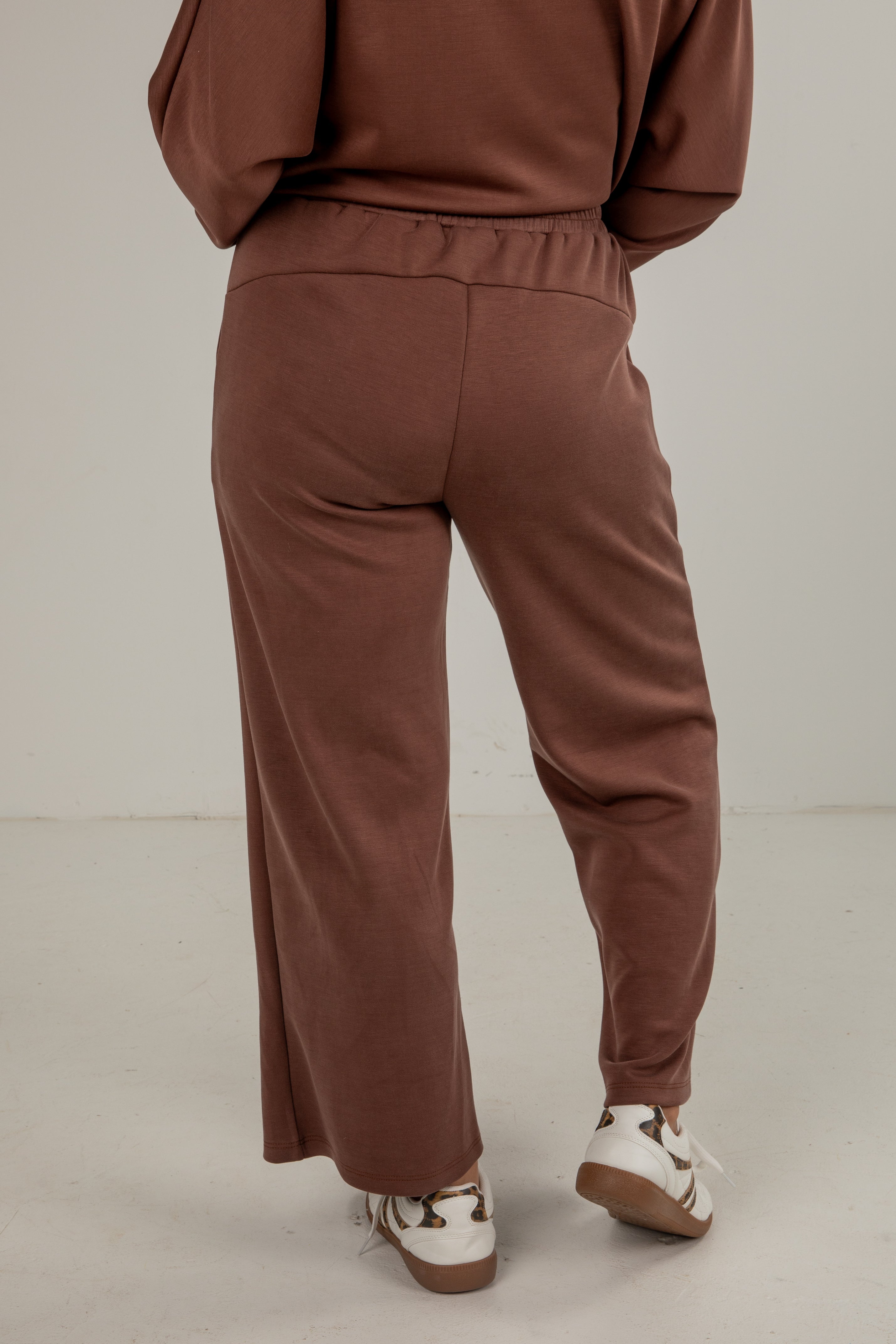Brown tracksuit worn by a person on a plain background
