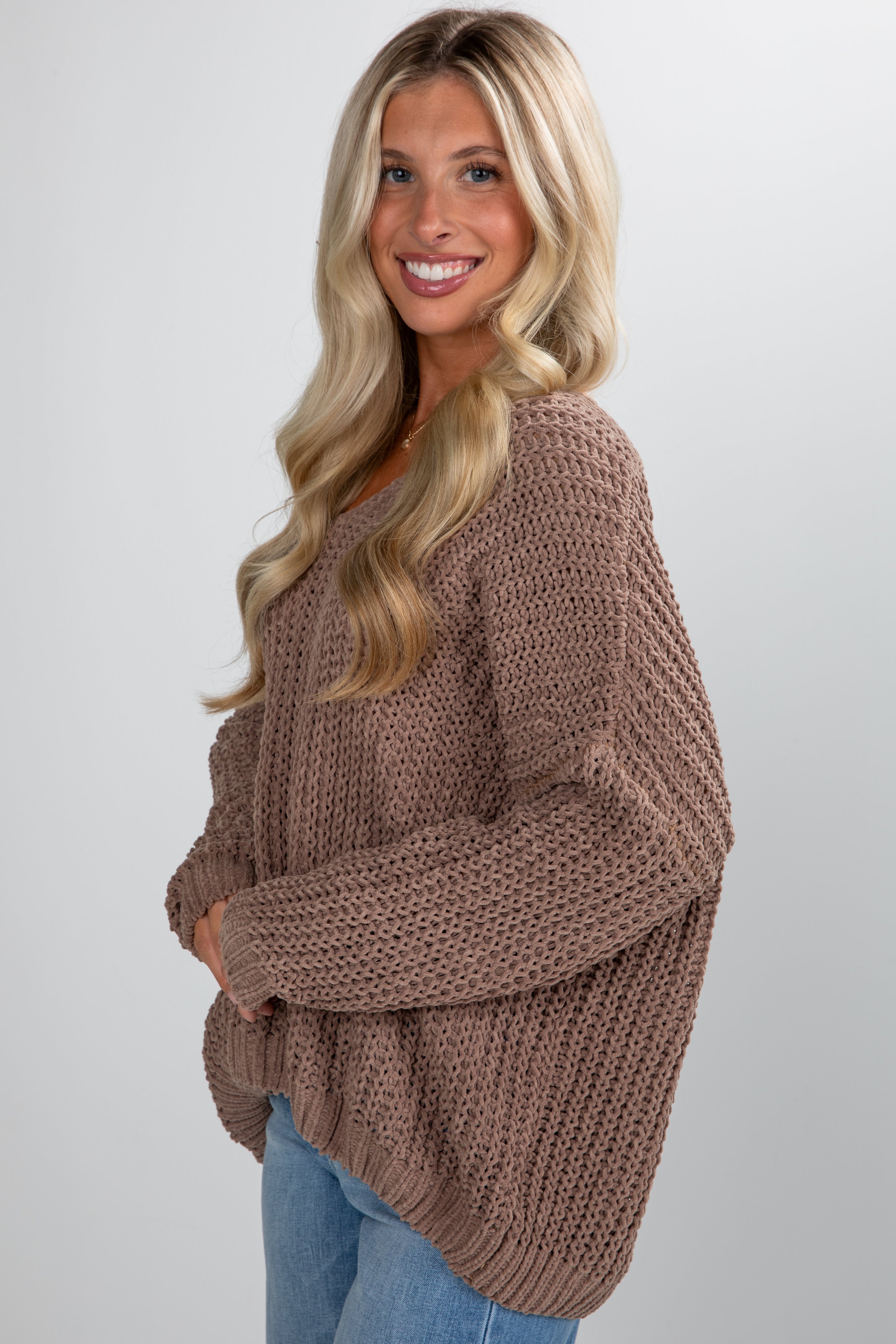 Woman wearing a brown chunky knit sweater on a plain background