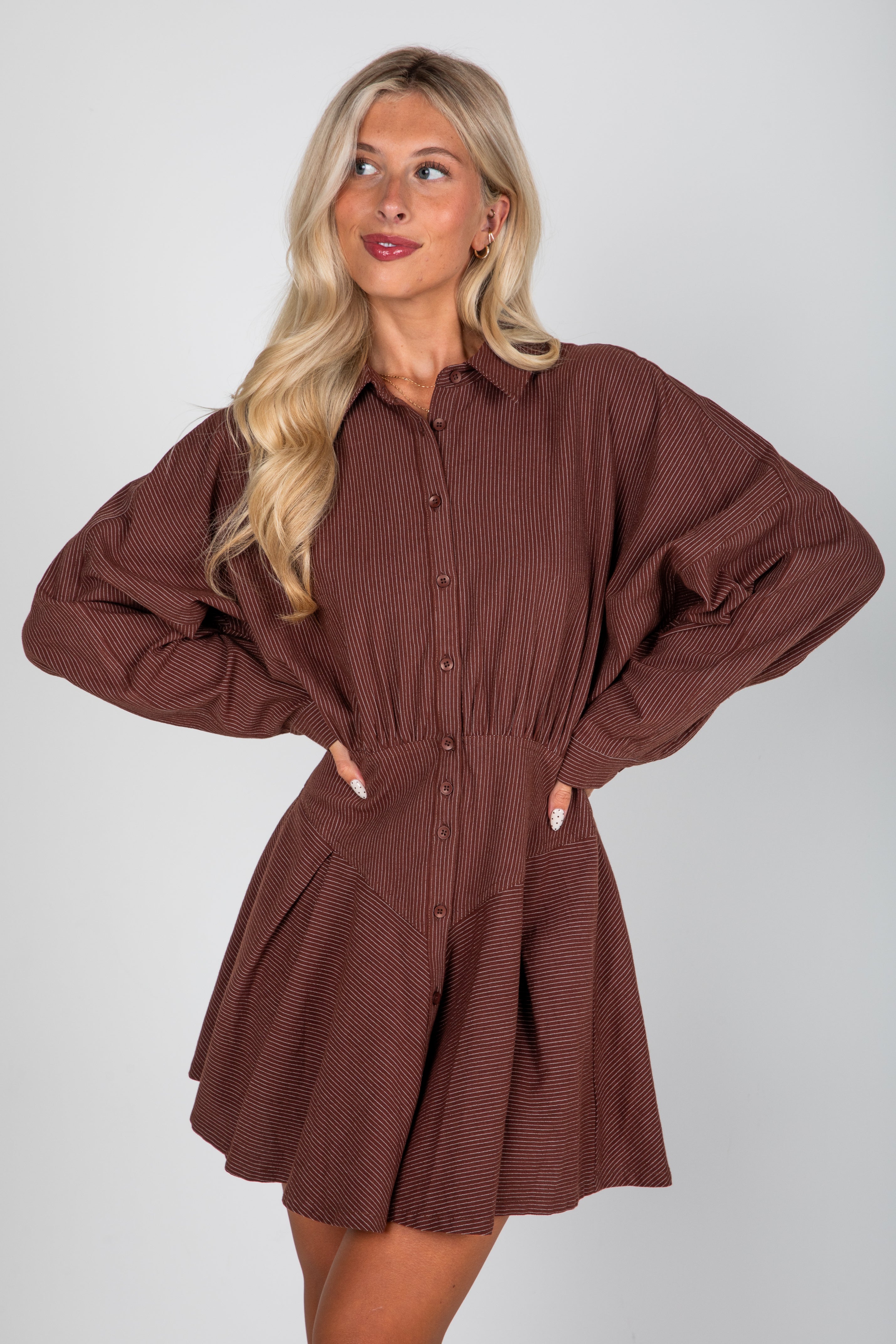 Woman wearing a brown ribbed dress against a white background