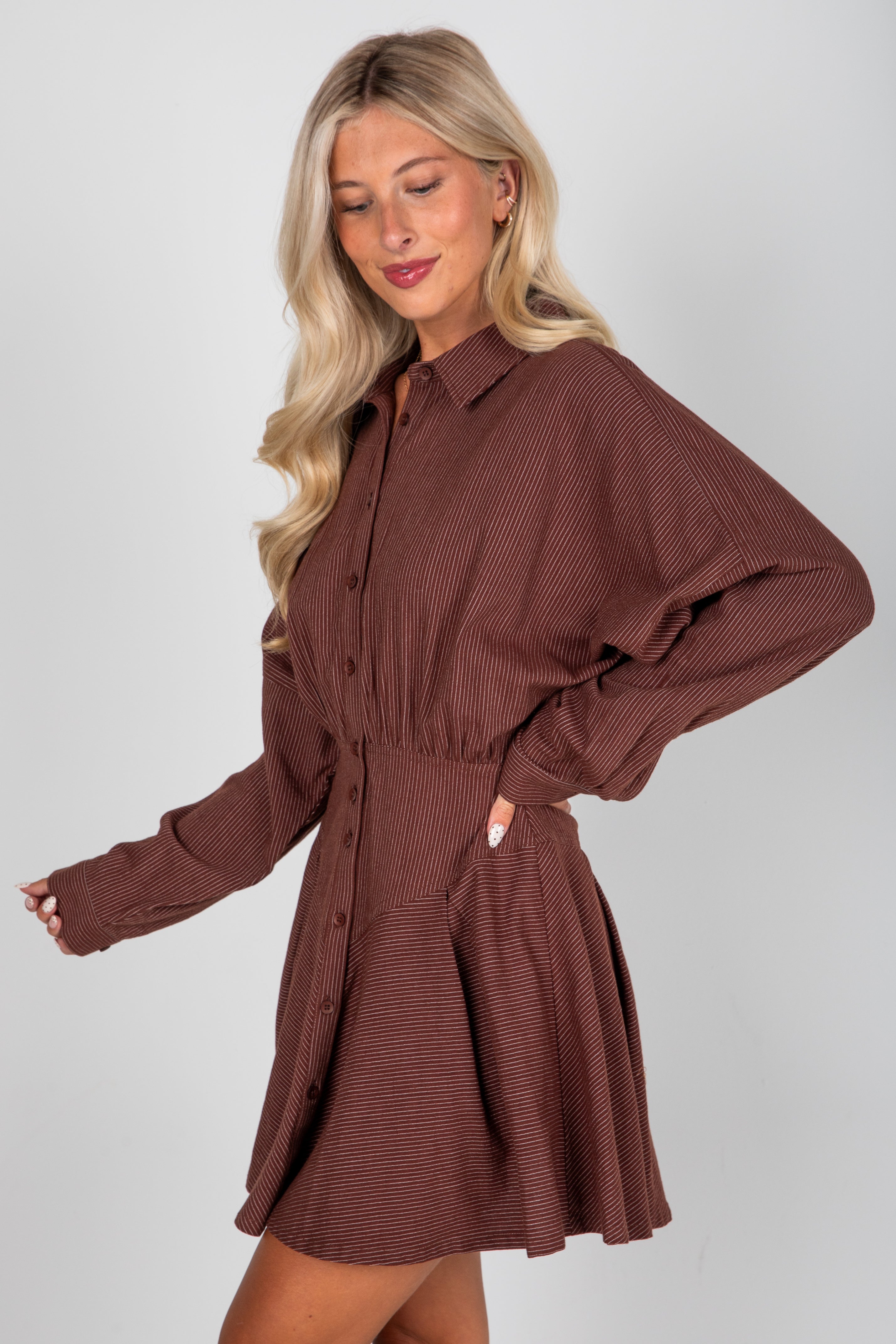 Woman wearing a brown dress against a plain background