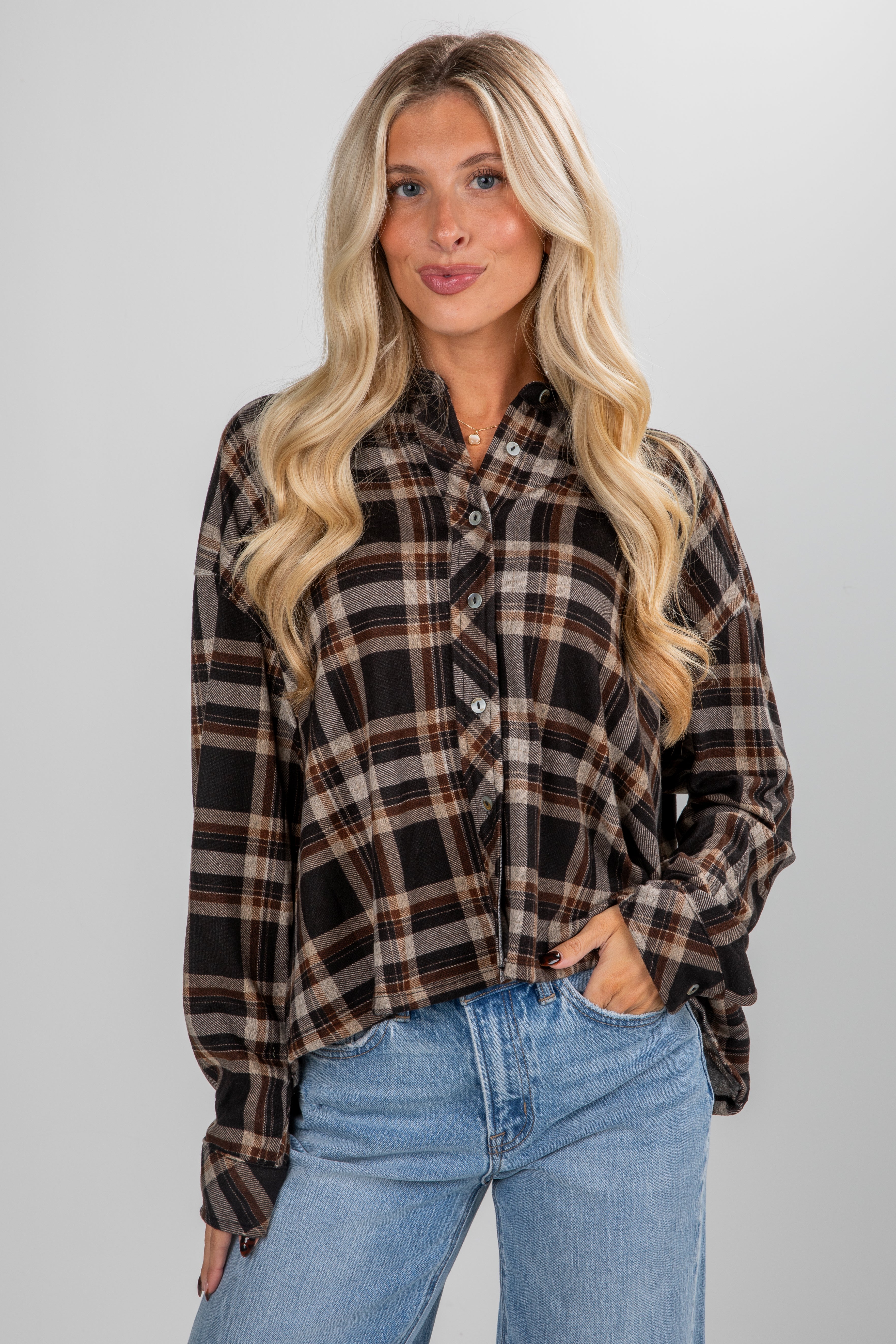 Woman wearing a plaid shirt and jeans on a plain background