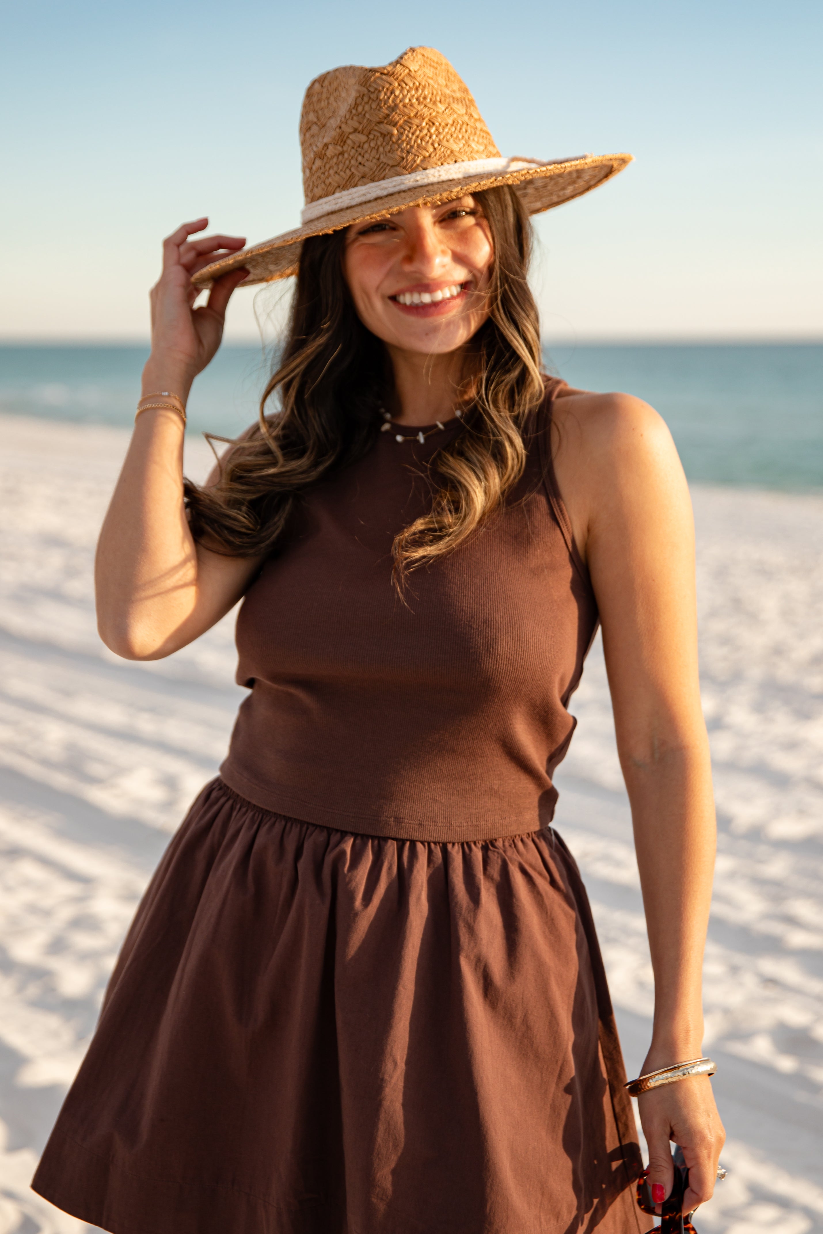 Woman in a brown dress and straw hat on a beach