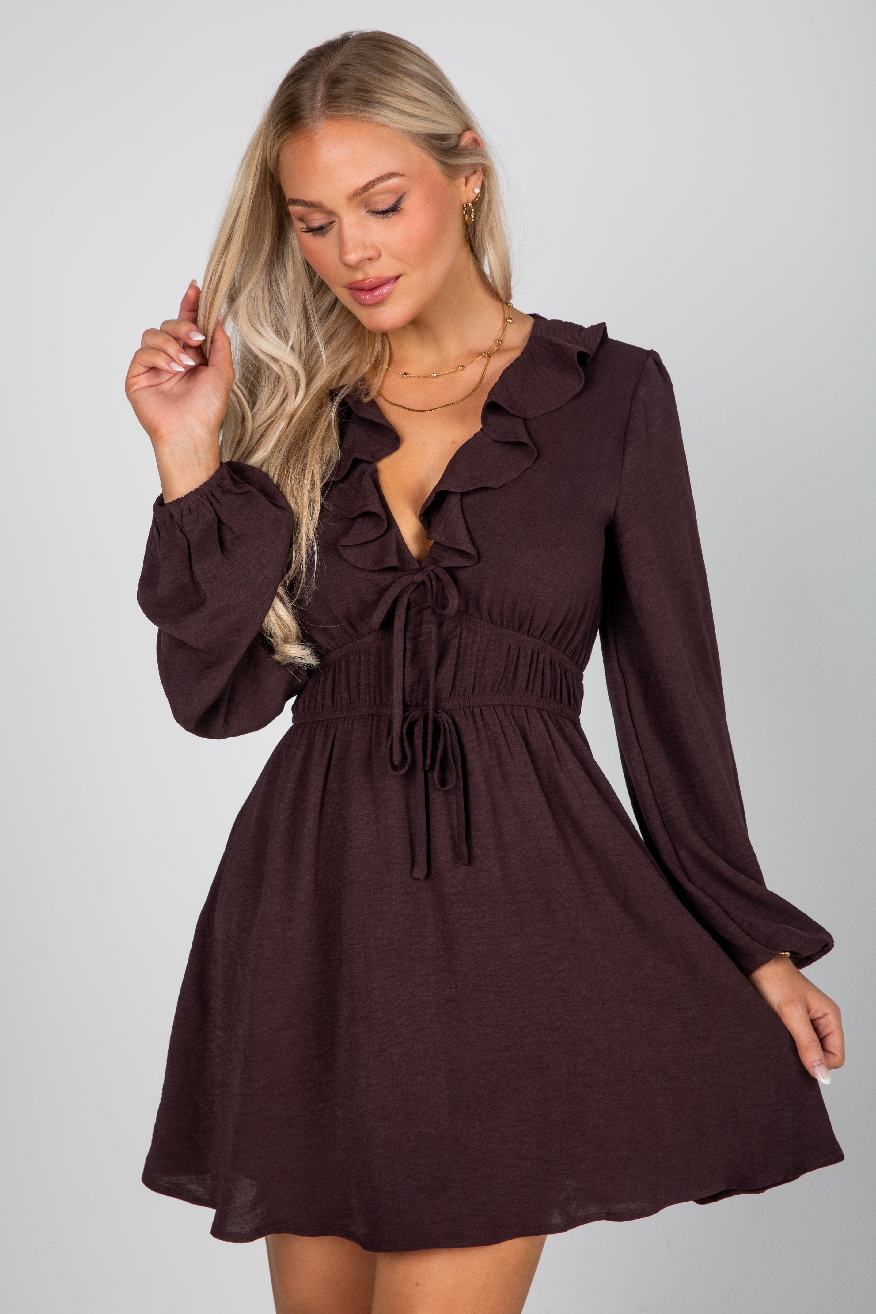 Woman wearing a brown dress with long sleeves on a plain background