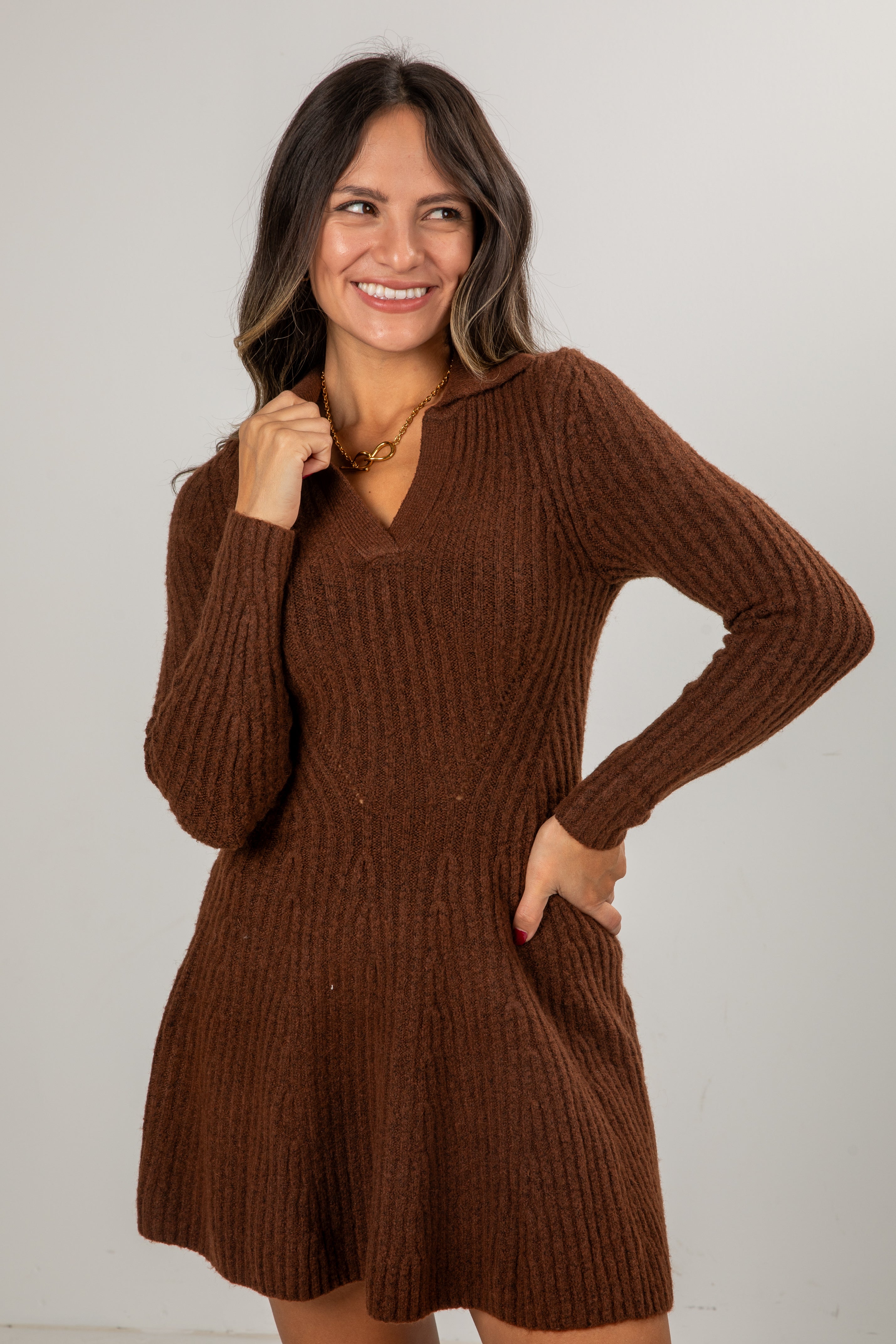 Woman wearing a brown ribbed knit dress against a plain background