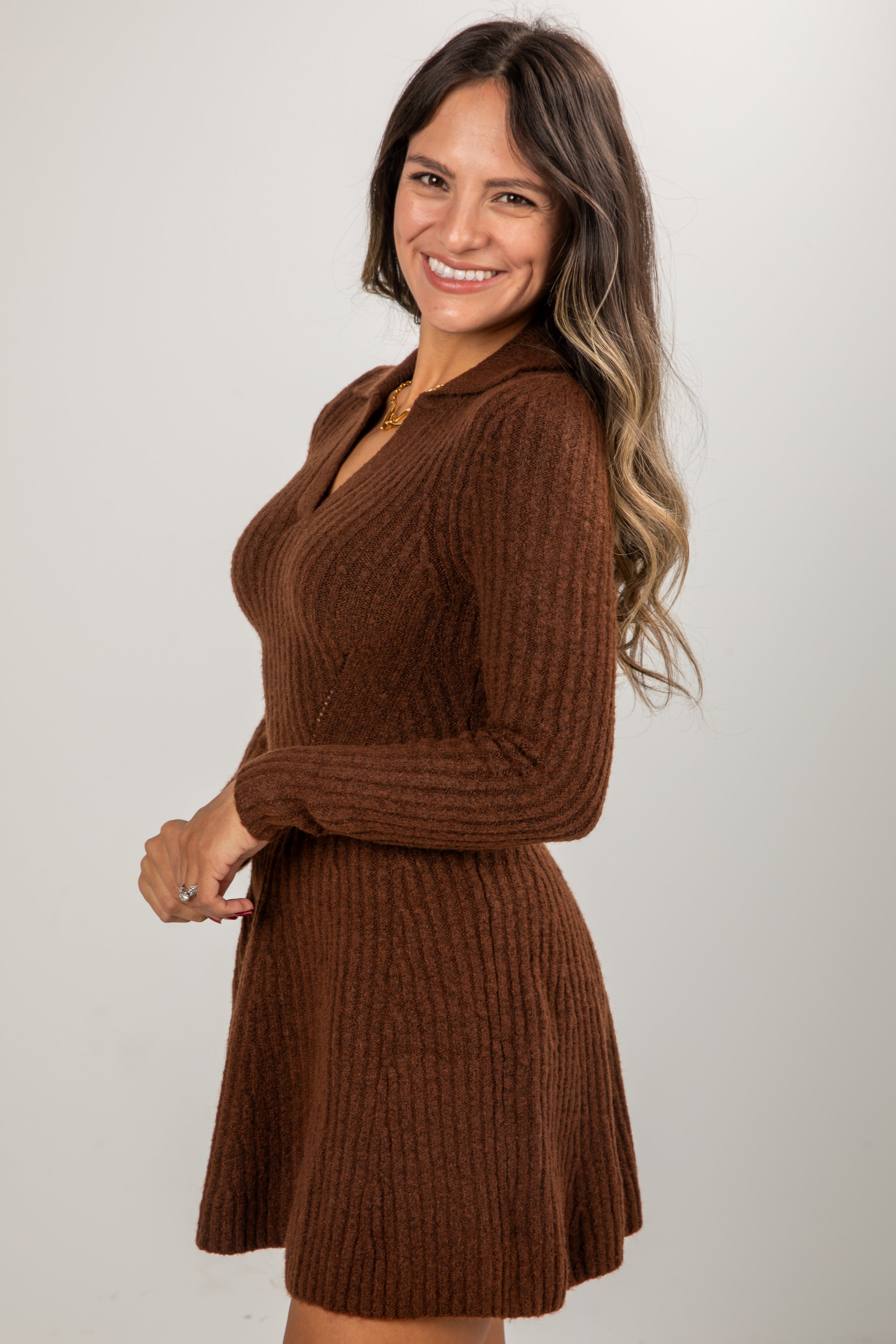 Woman wearing a brown ribbed knit dress against a plain background
