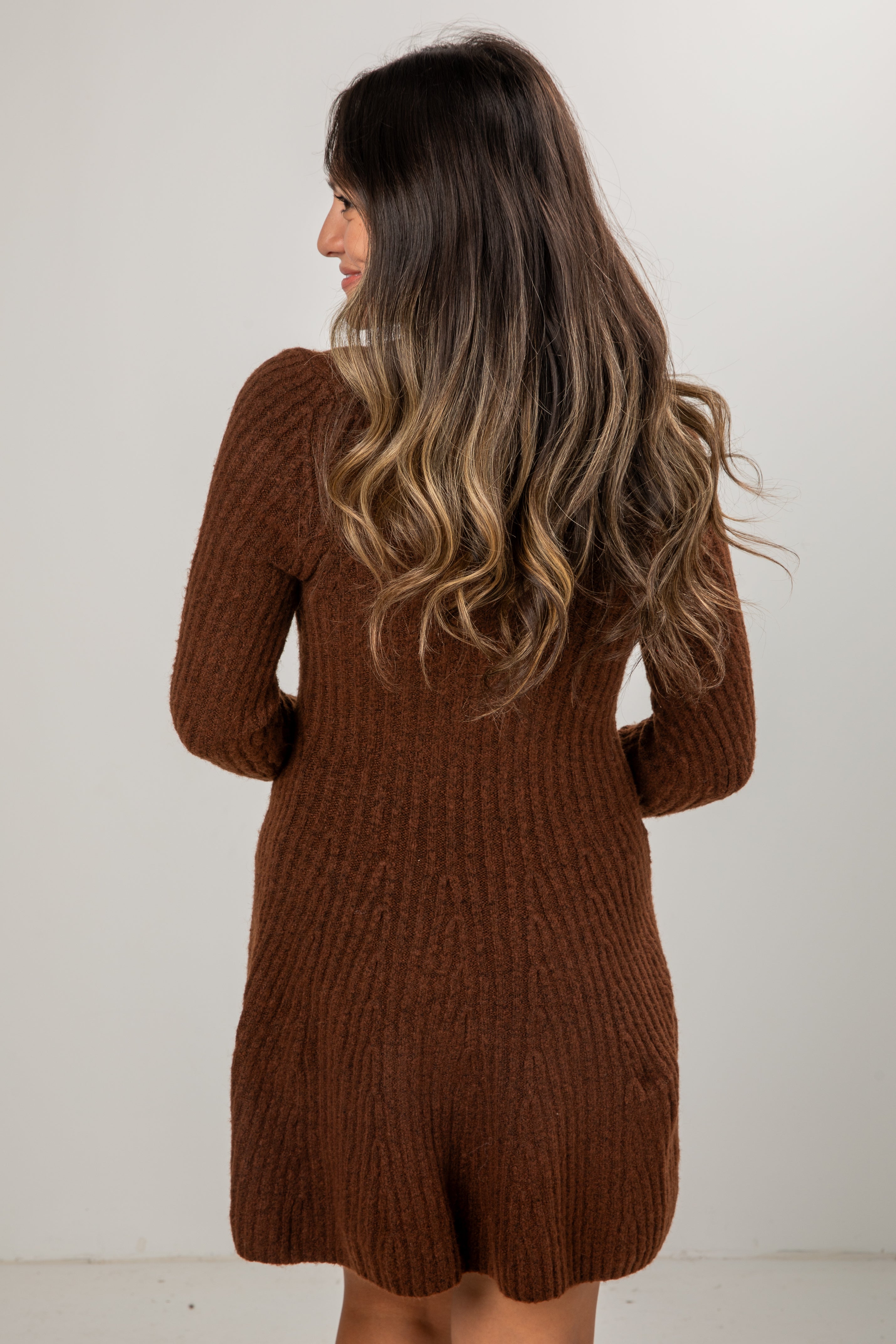 Woman wearing a brown knitted dress against a white background