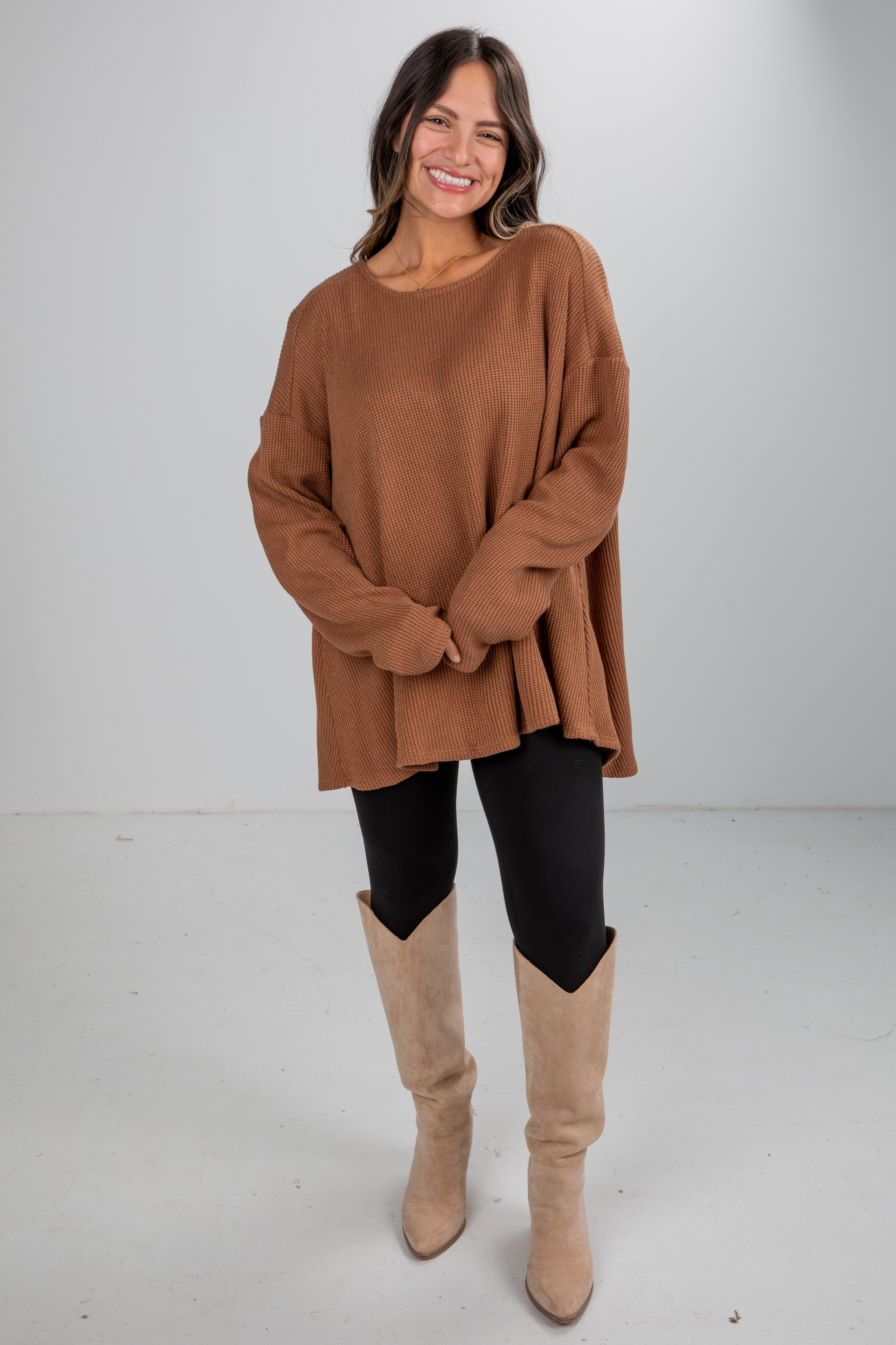 Woman wearing a brown sweater and beige knee-high boots on a white background