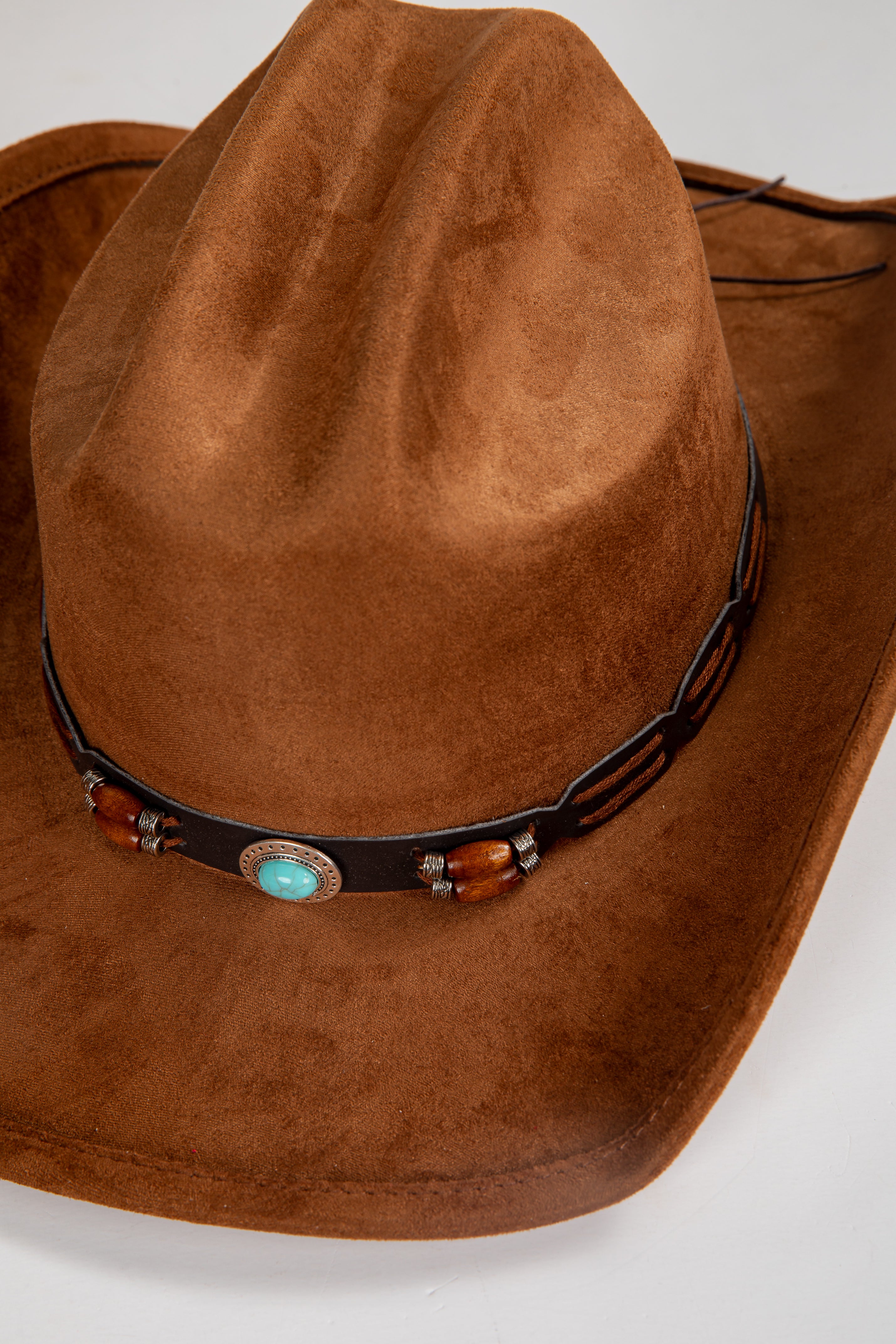 Brown cowboy hat with decorative band featuring turquoise stone and wooden beads on a white background