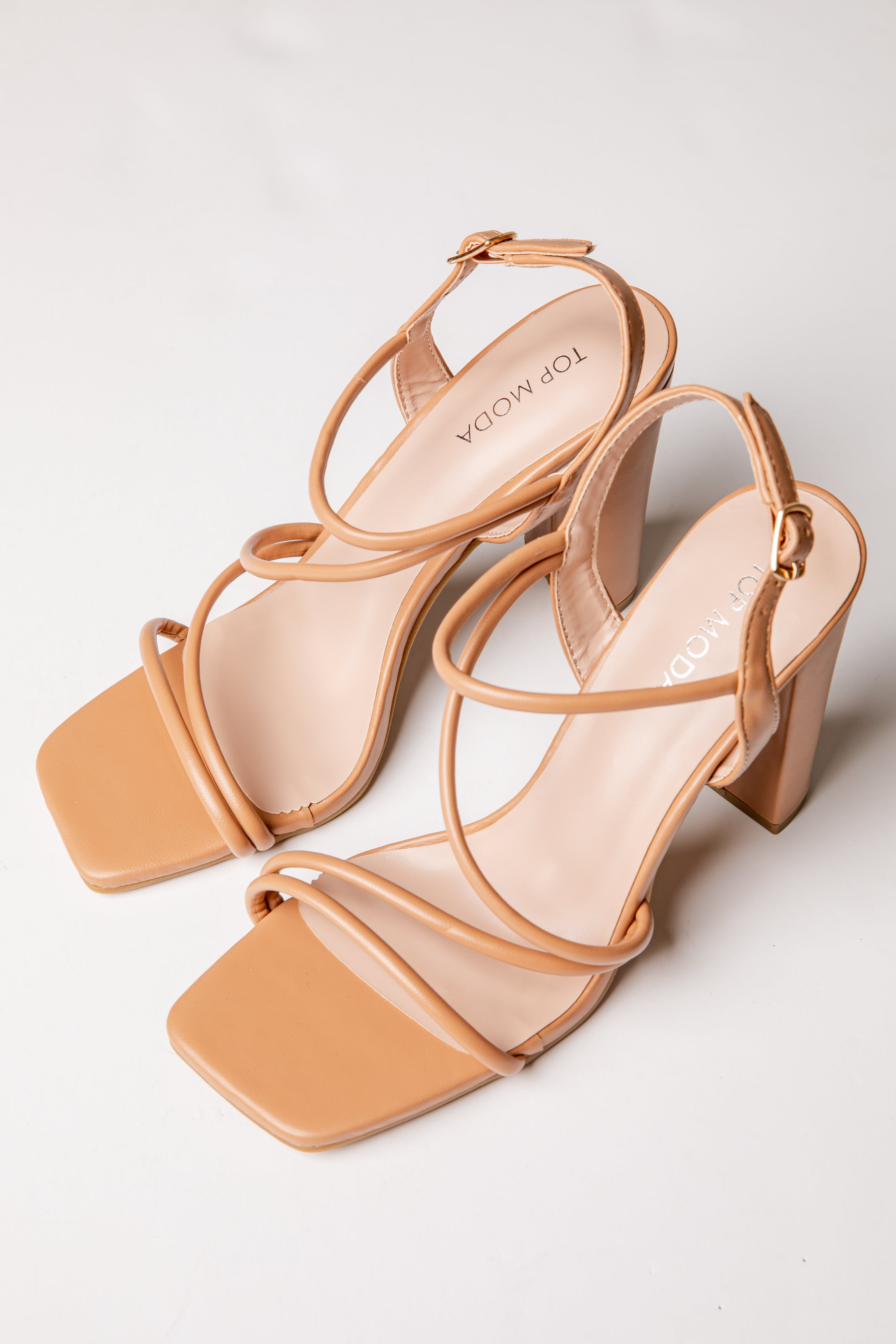 Pair of tan high-heeled sandals on a light gray background