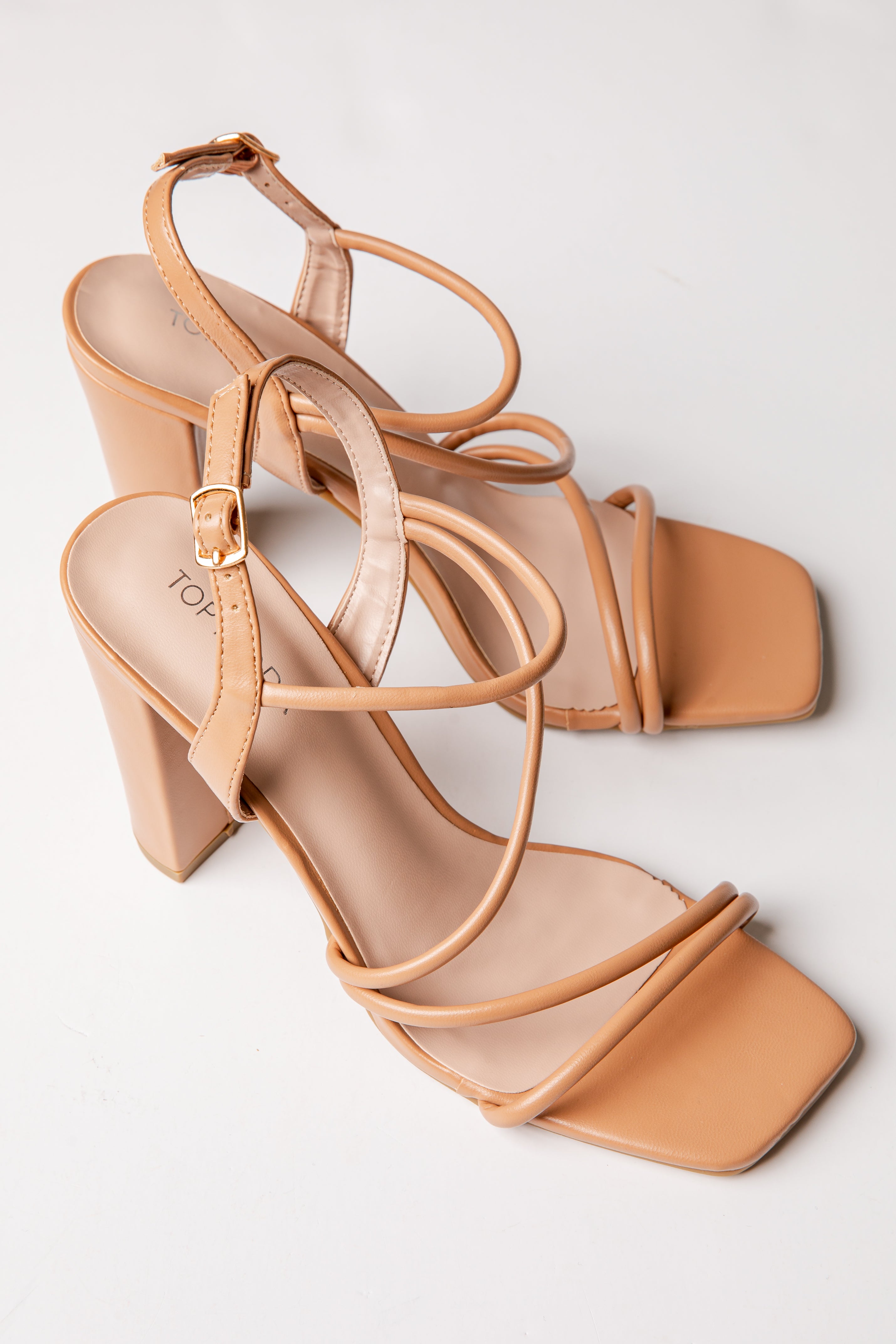 Tan high-heeled sandals with multiple straps on a light gray background