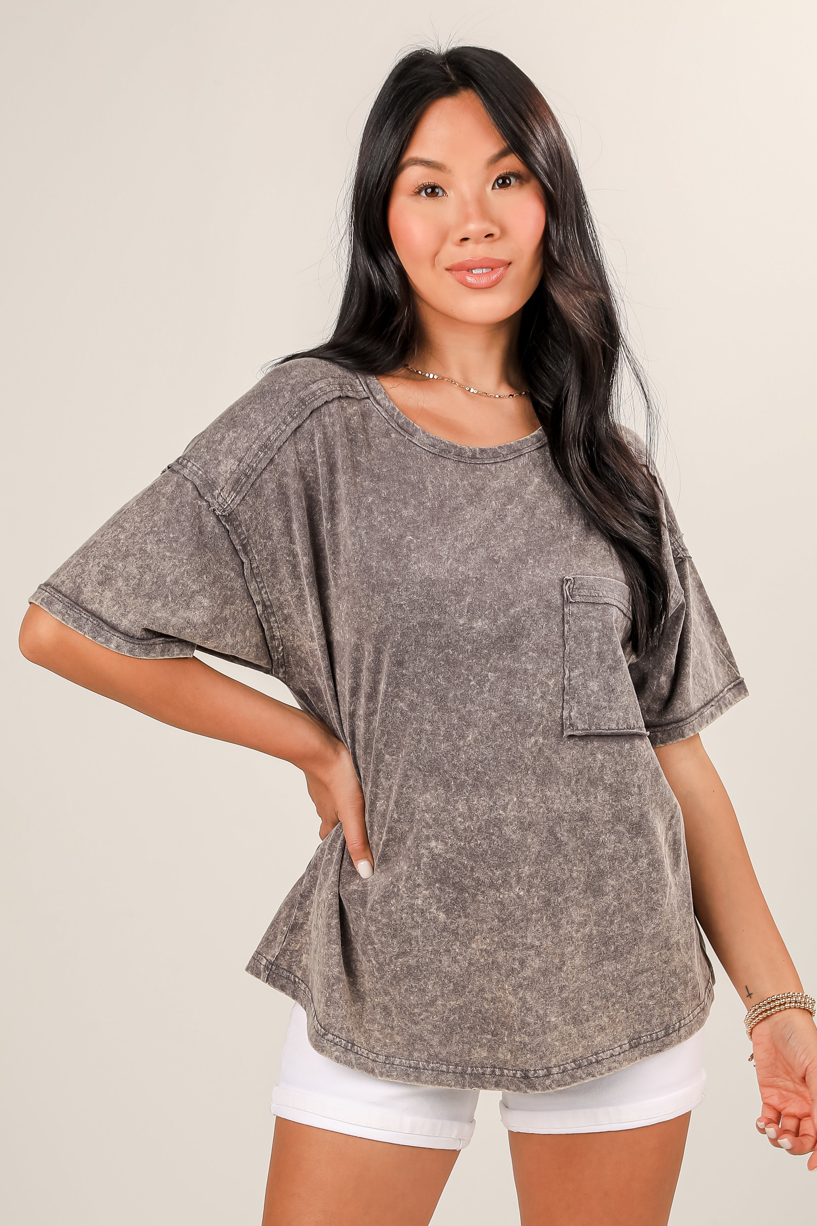 Woman wearing a gray oversized t-shirt with a pocket on a plain background