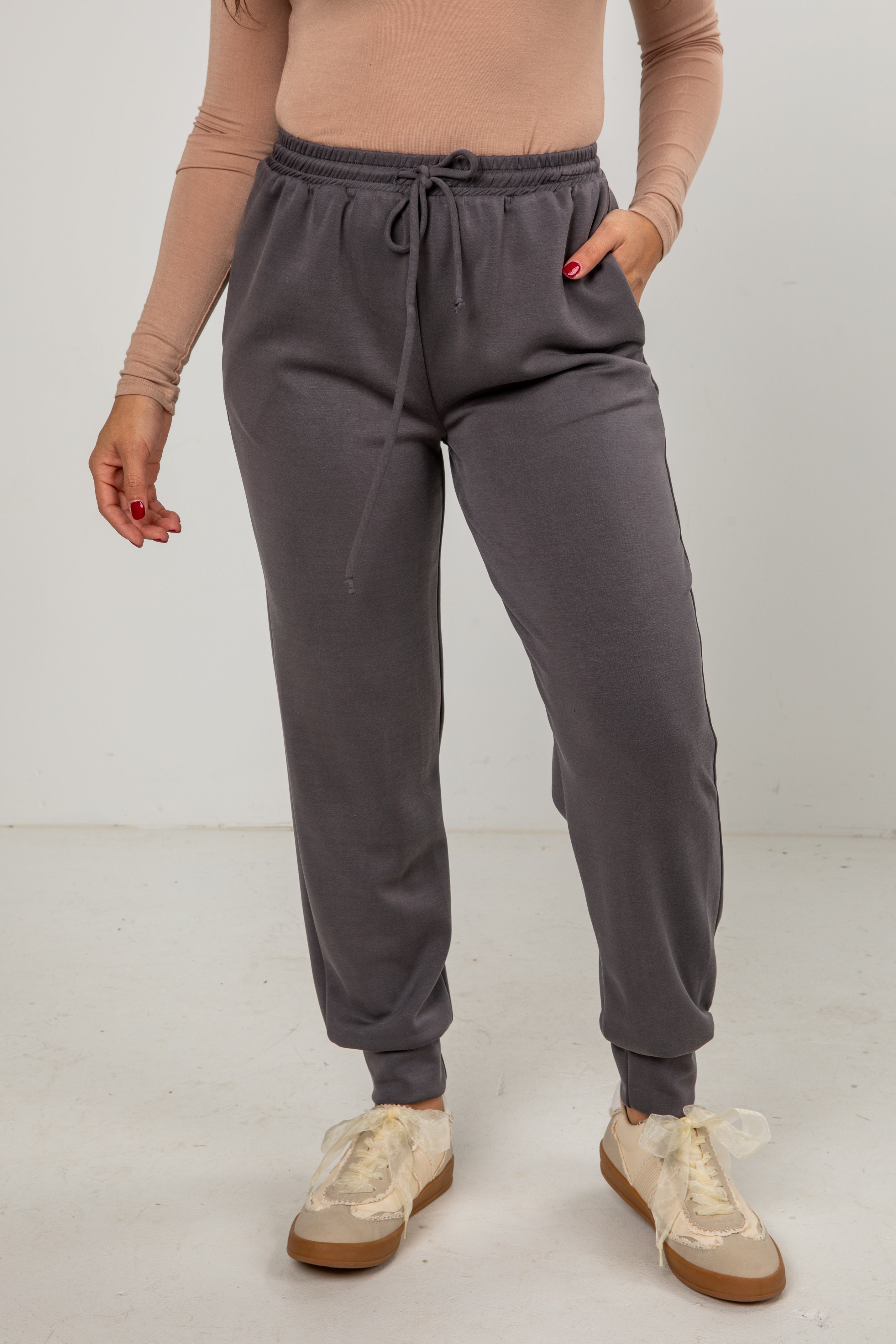 Person wearing gray sweatpants and beige sneakers on a white background