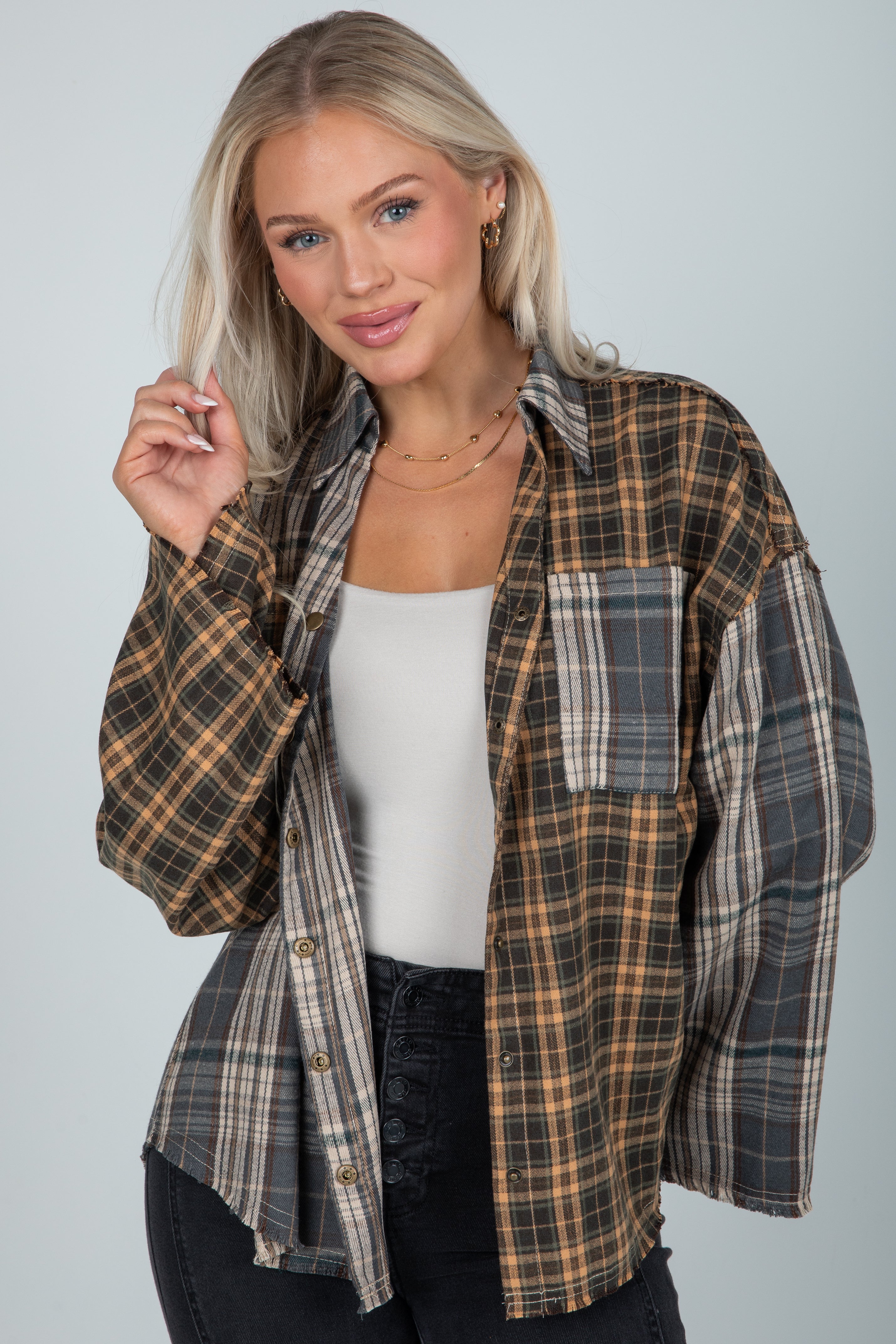 Woman wearing a plaid shirt over a white top with a gray background