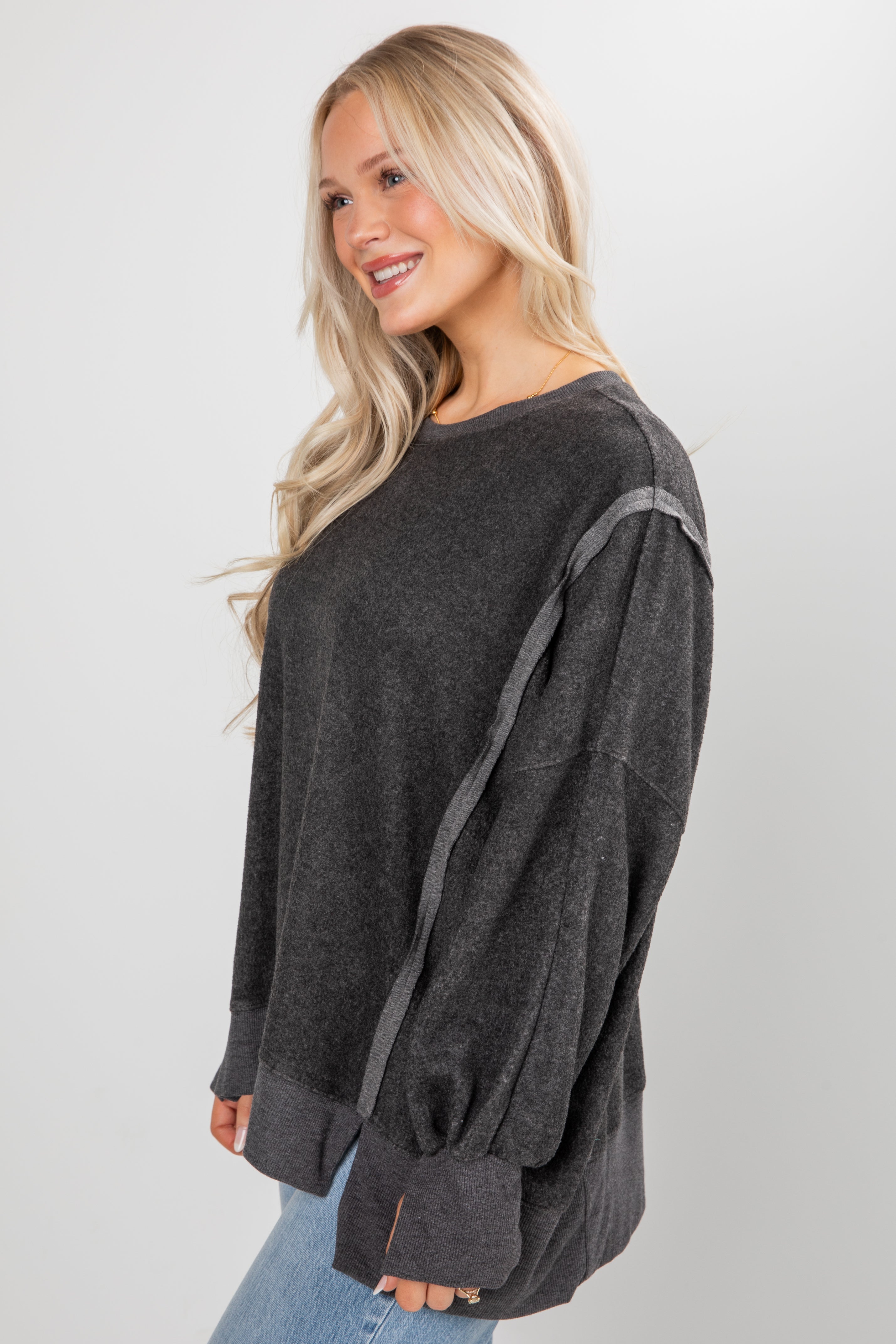 Woman wearing a dark gray oversized sweater with a white background