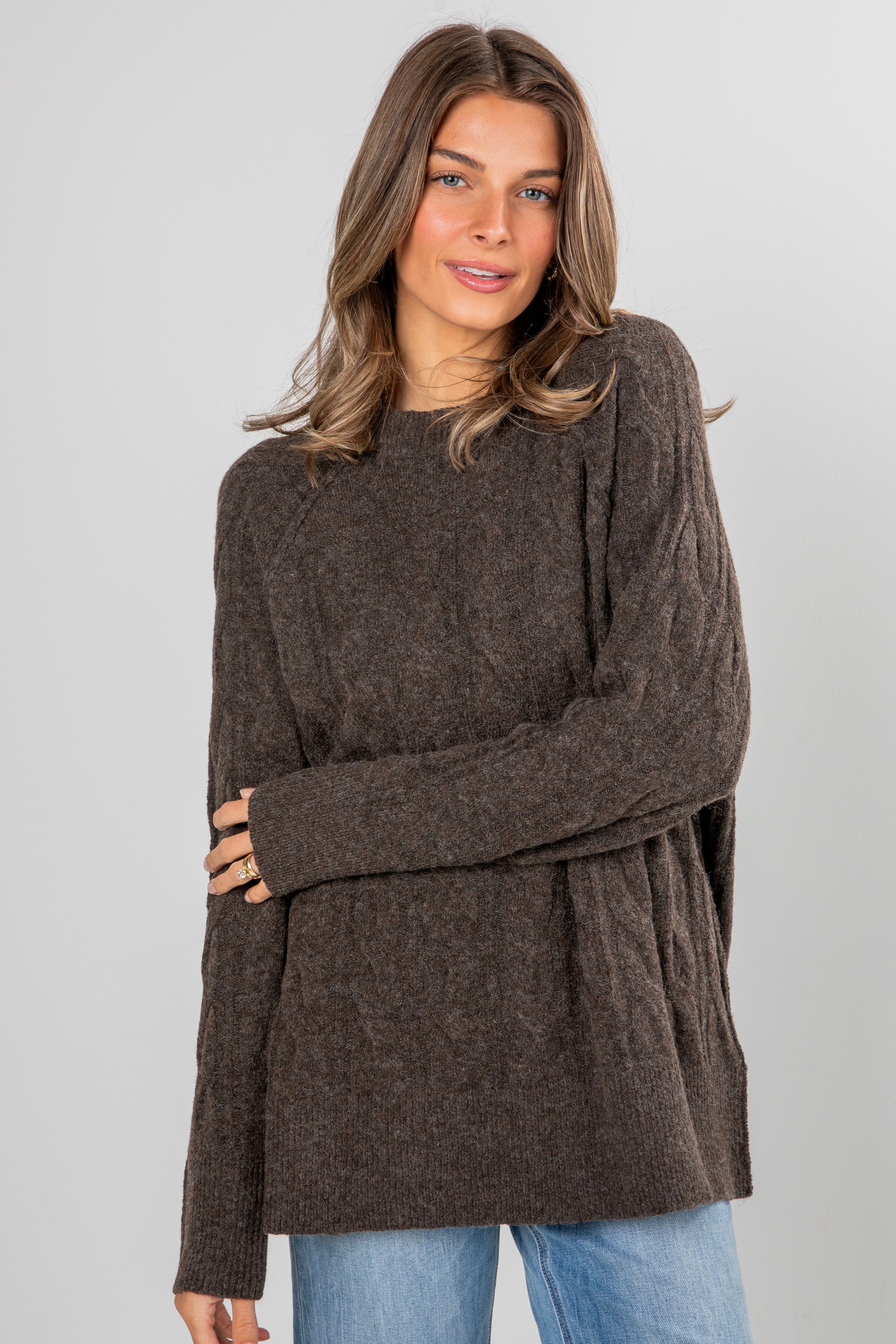 Woman wearing a brown sweater with a plain background