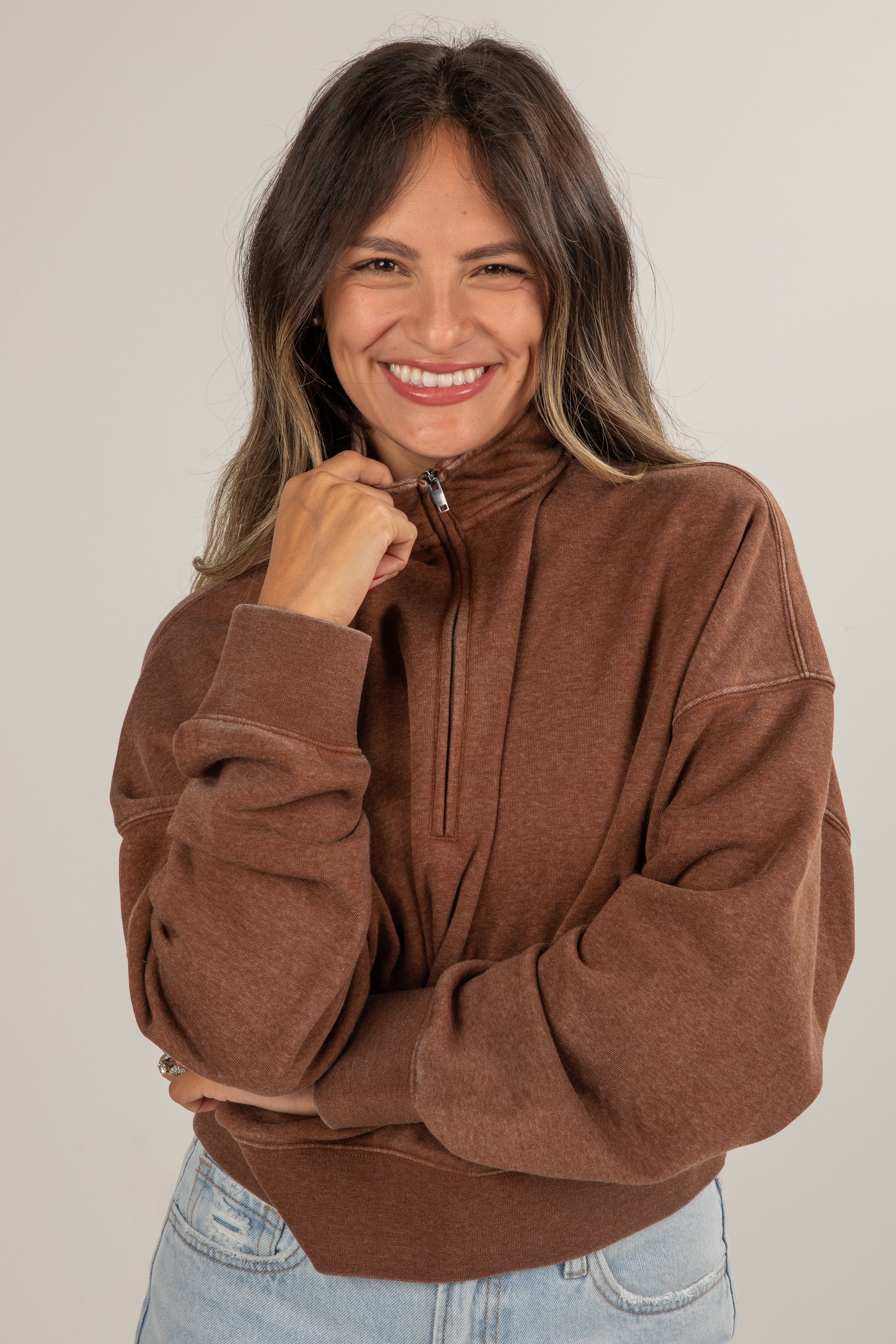 Woman wearing a brown pullover with a neutral background