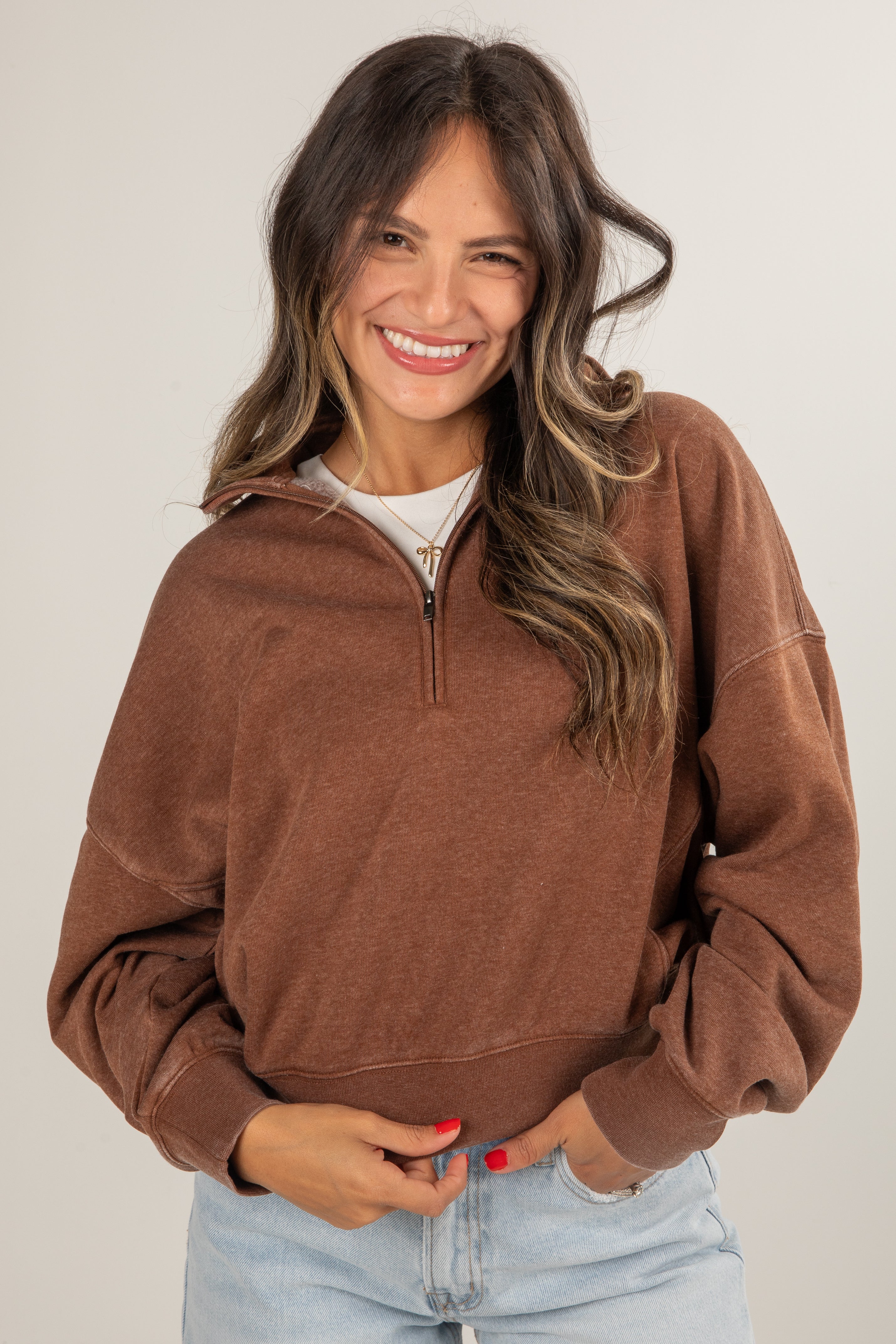 Woman wearing a brown half-zip sweatshirt against a plain background