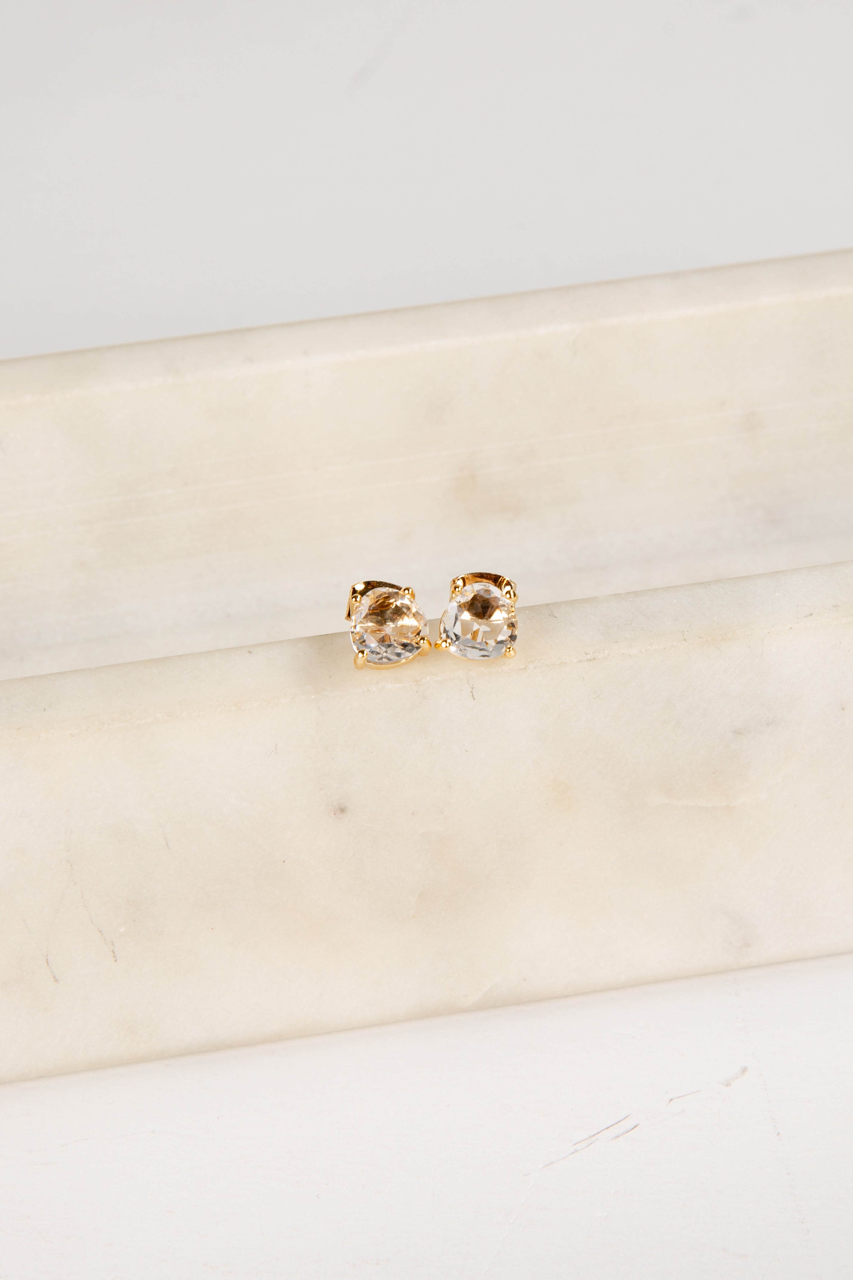 Gold and silver earrings on a beige fabric background