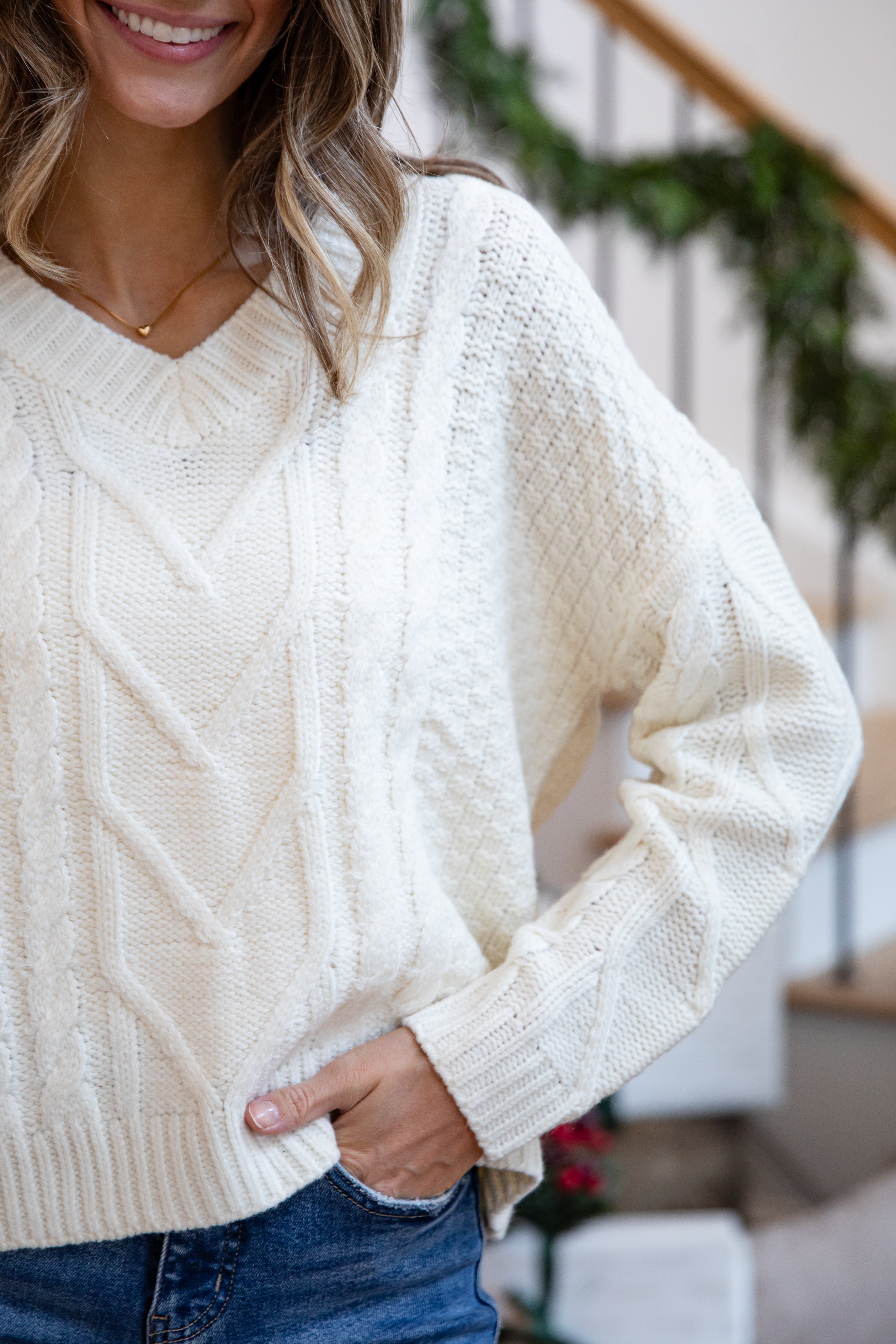Person wearing a cream sweater with a blurred indoor background