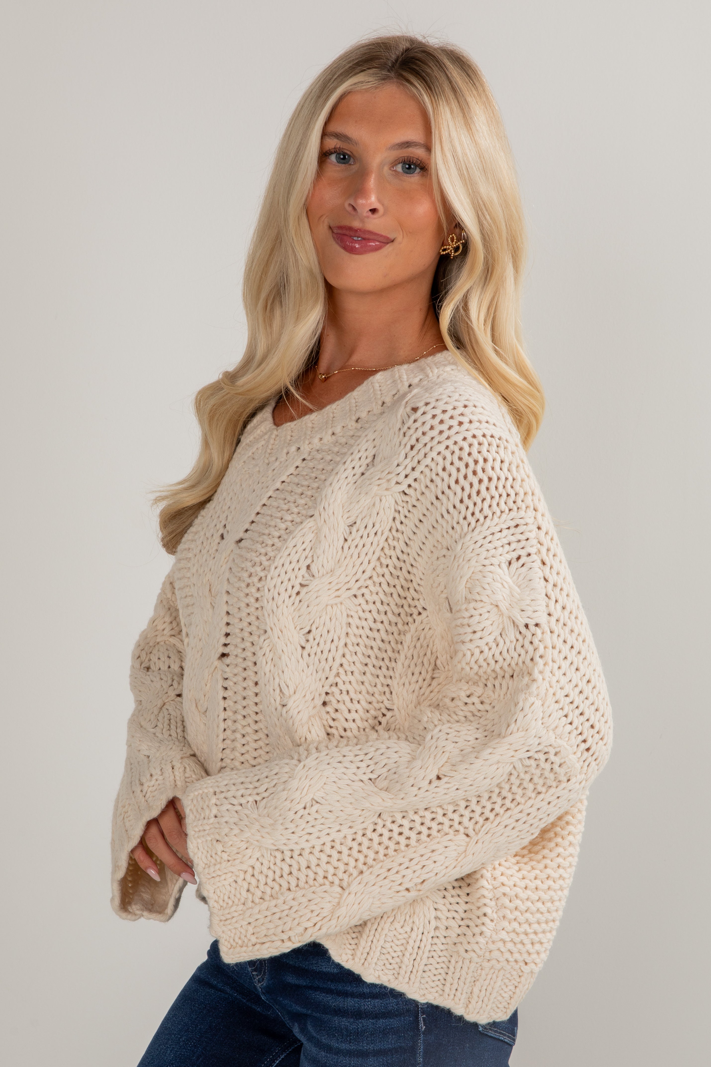 Woman wearing a beige knitted sweater against a plain background