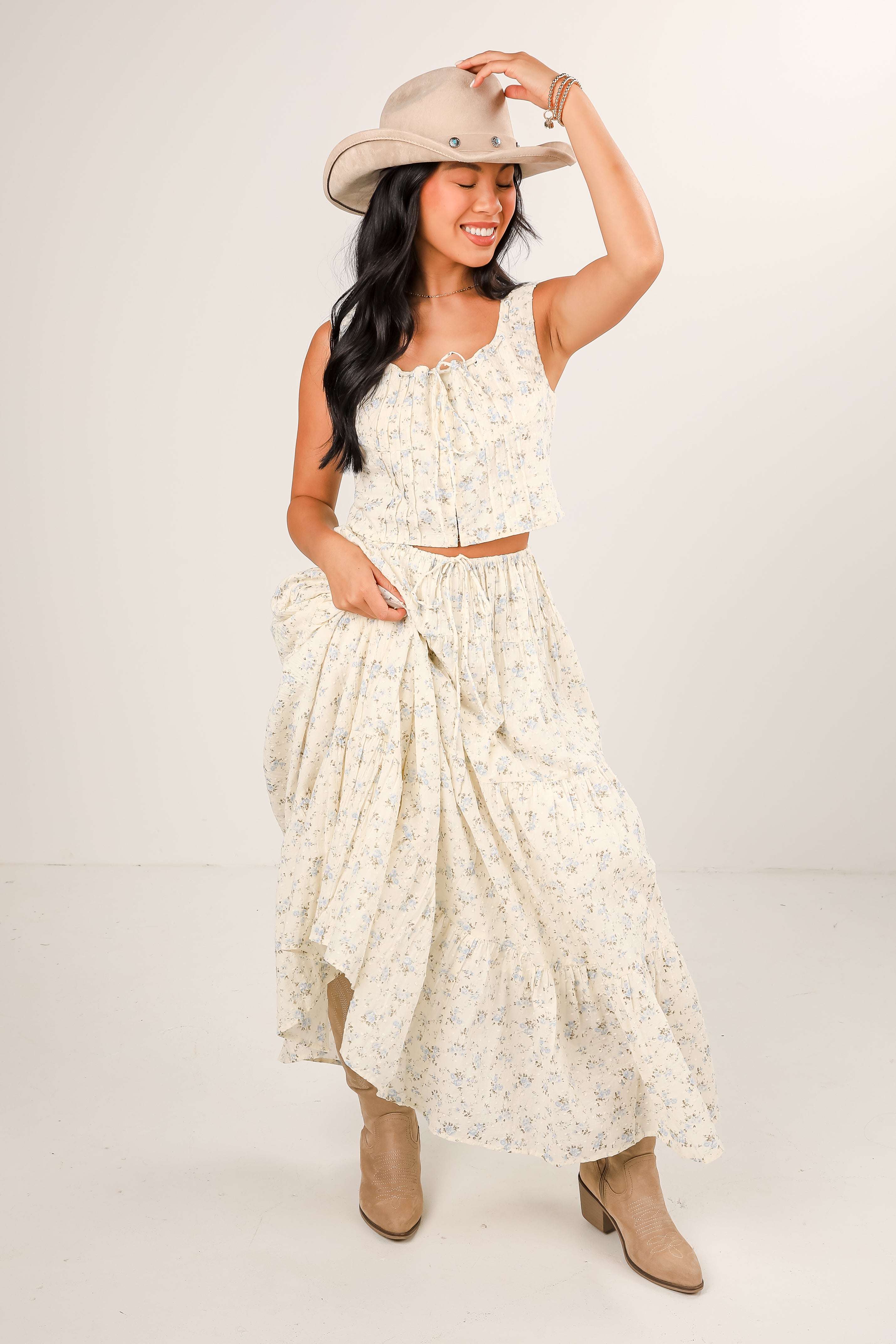 Woman wearing a white floral dress and beige hat on a plain background