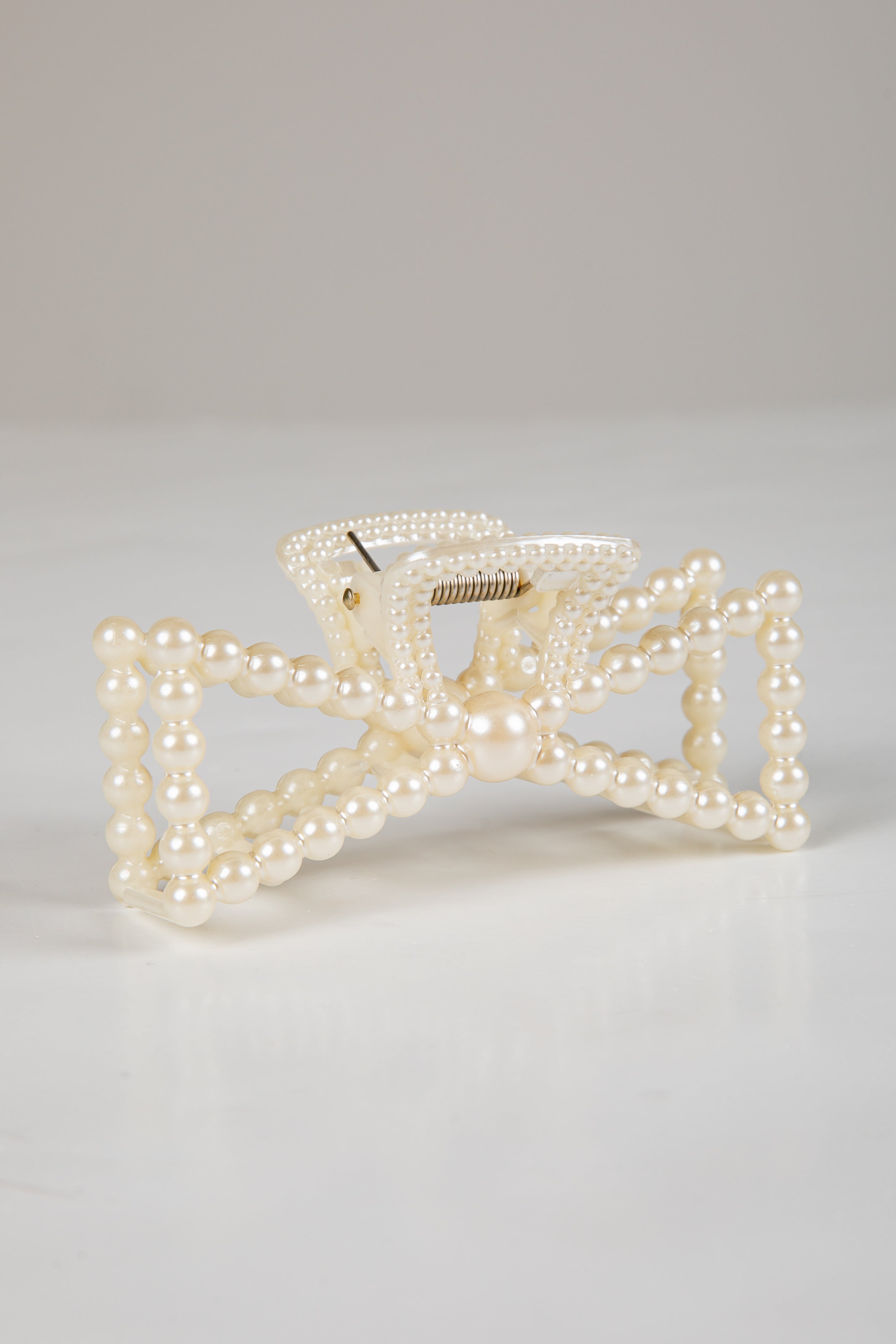 Pearl bow hair clip on a light gray background