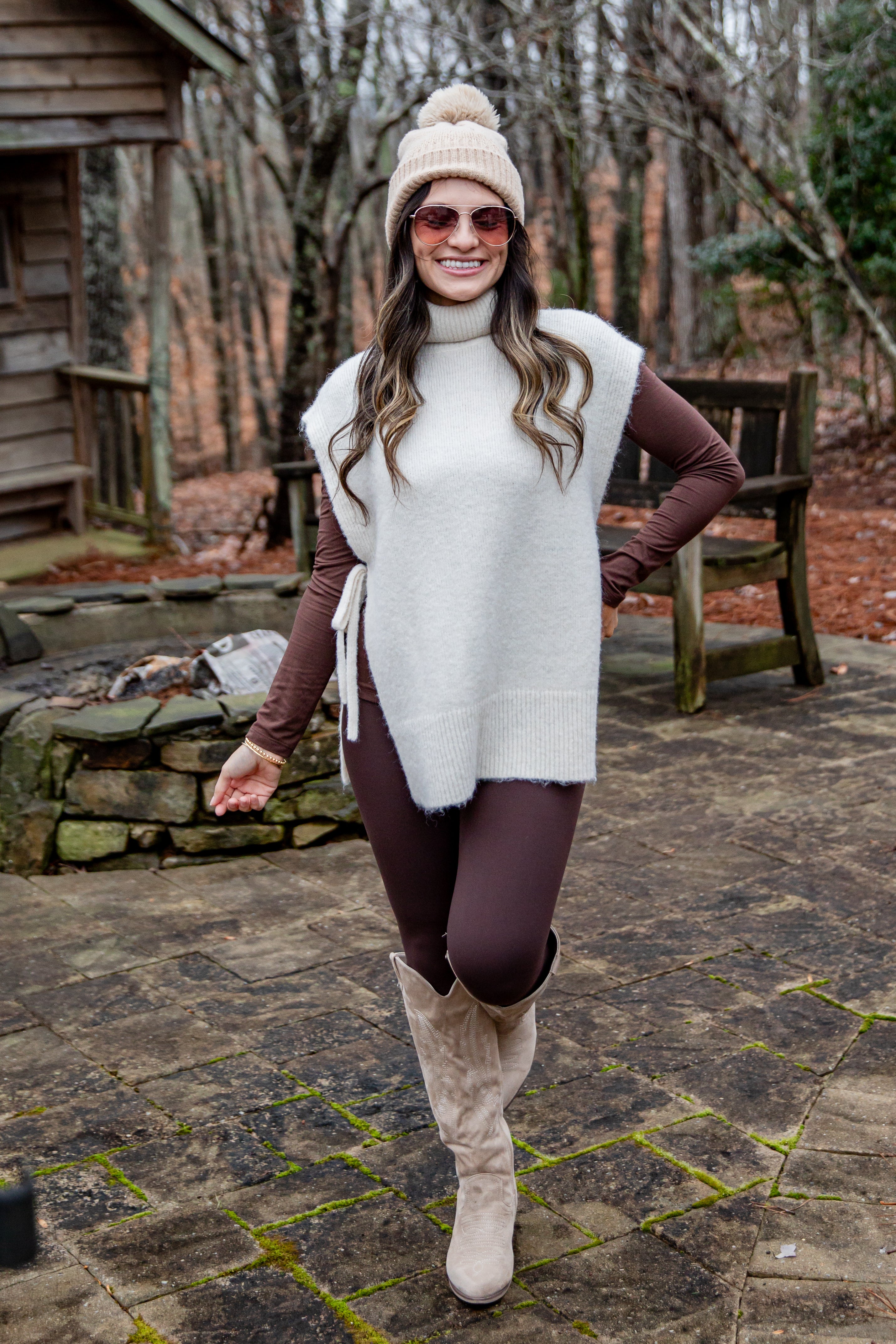 Woman in winter clothing standing outdoors on a stone path with trees in the background