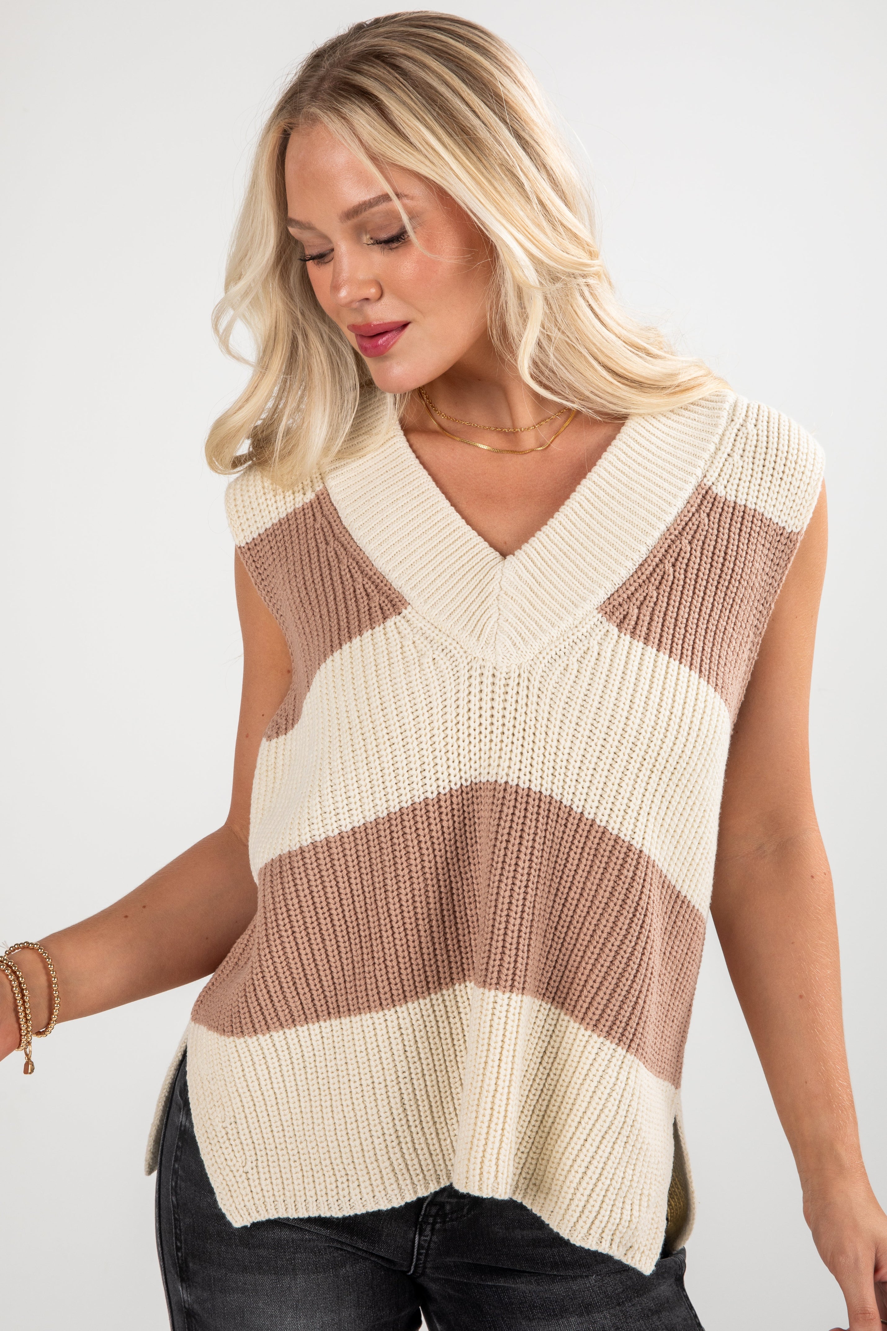 Woman wearing a striped sleeveless sweater against a white background