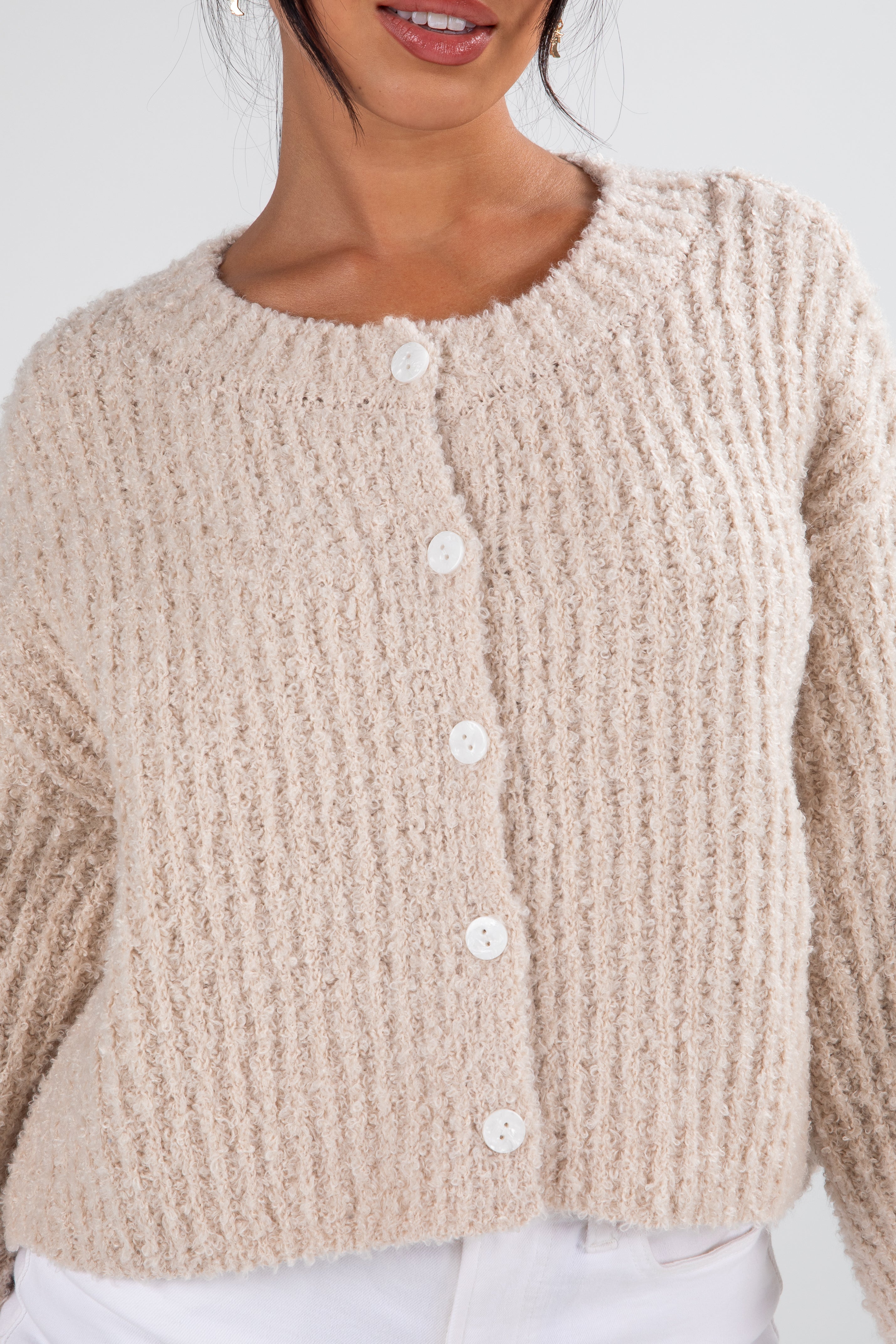 Beige knitted cardigan worn by a person on a light background