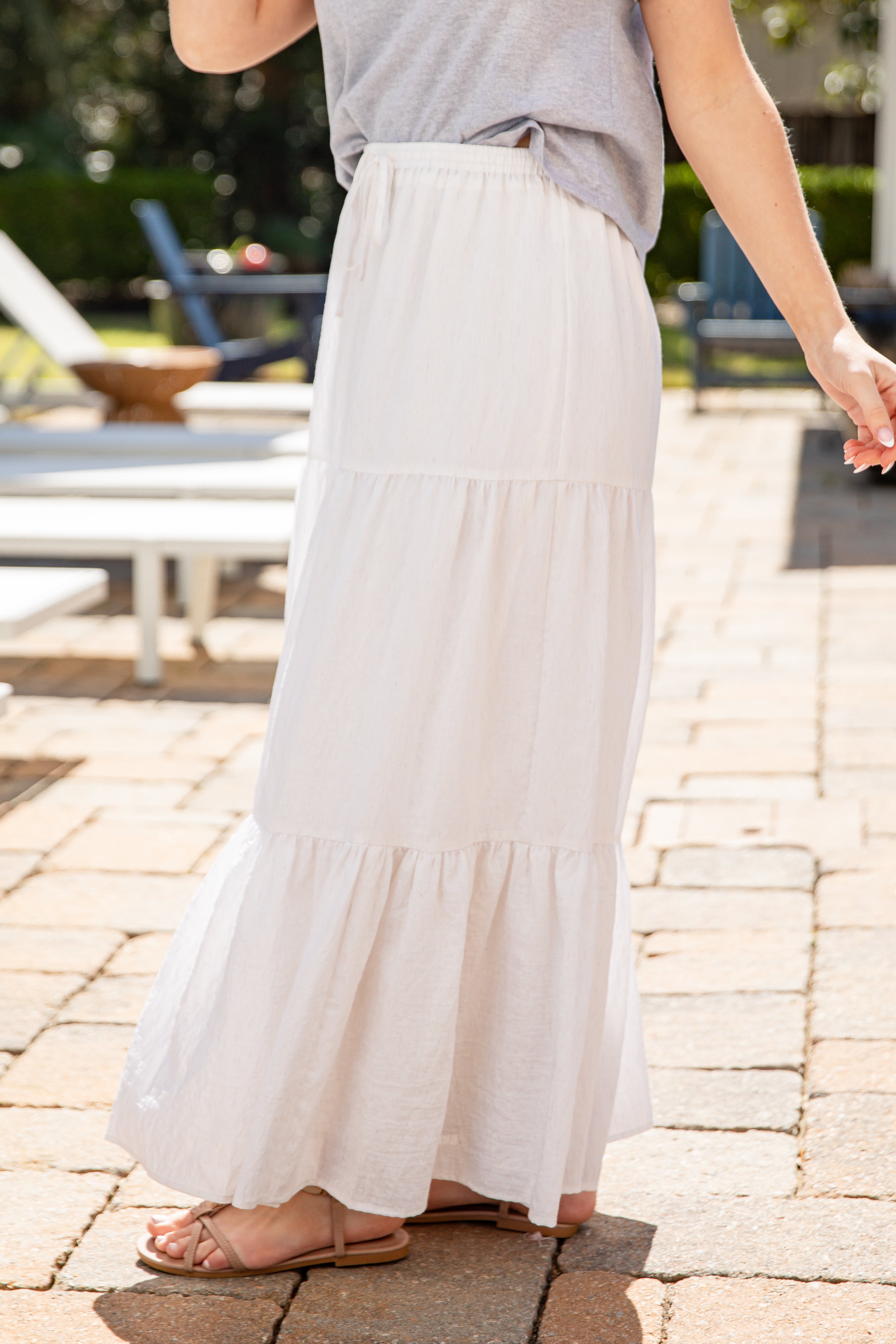 Person wearing a white skirt and gray top on a paved outdoor area.
