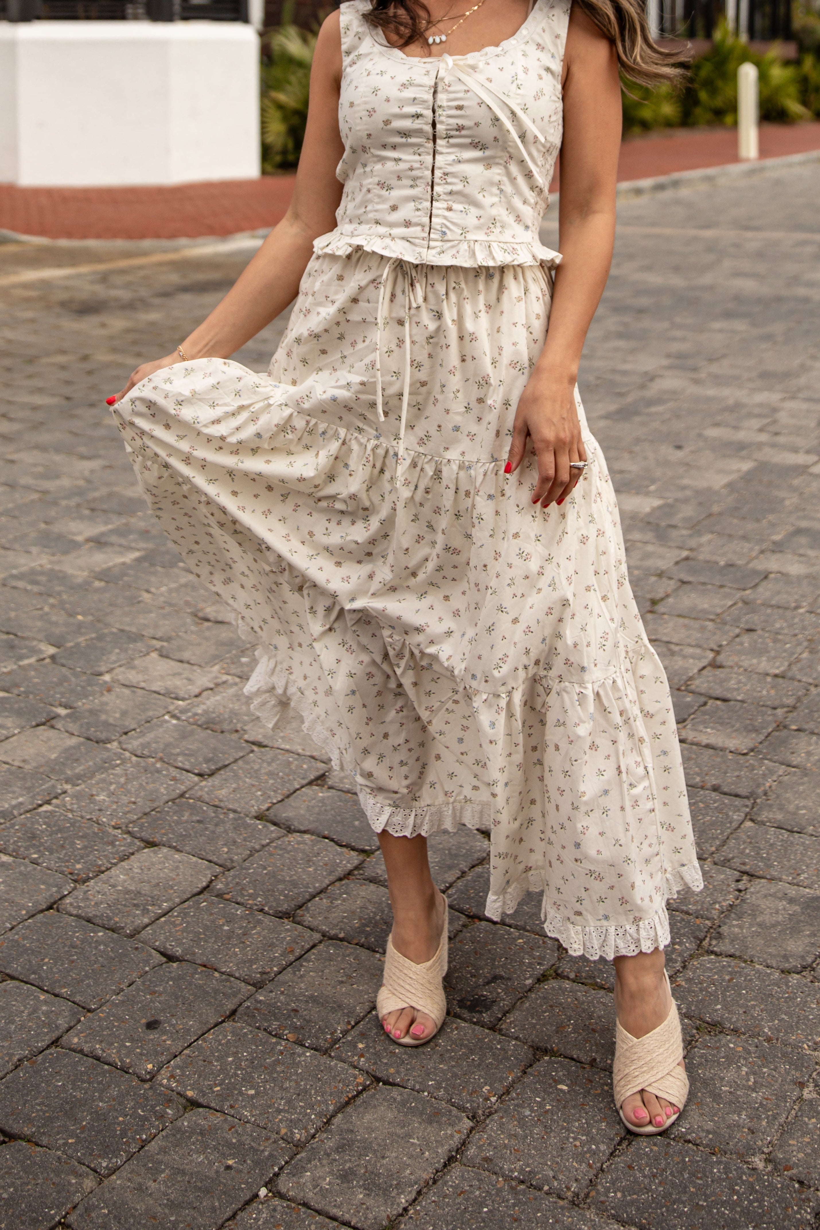 Woman wearing a white lace dress on a paved street.