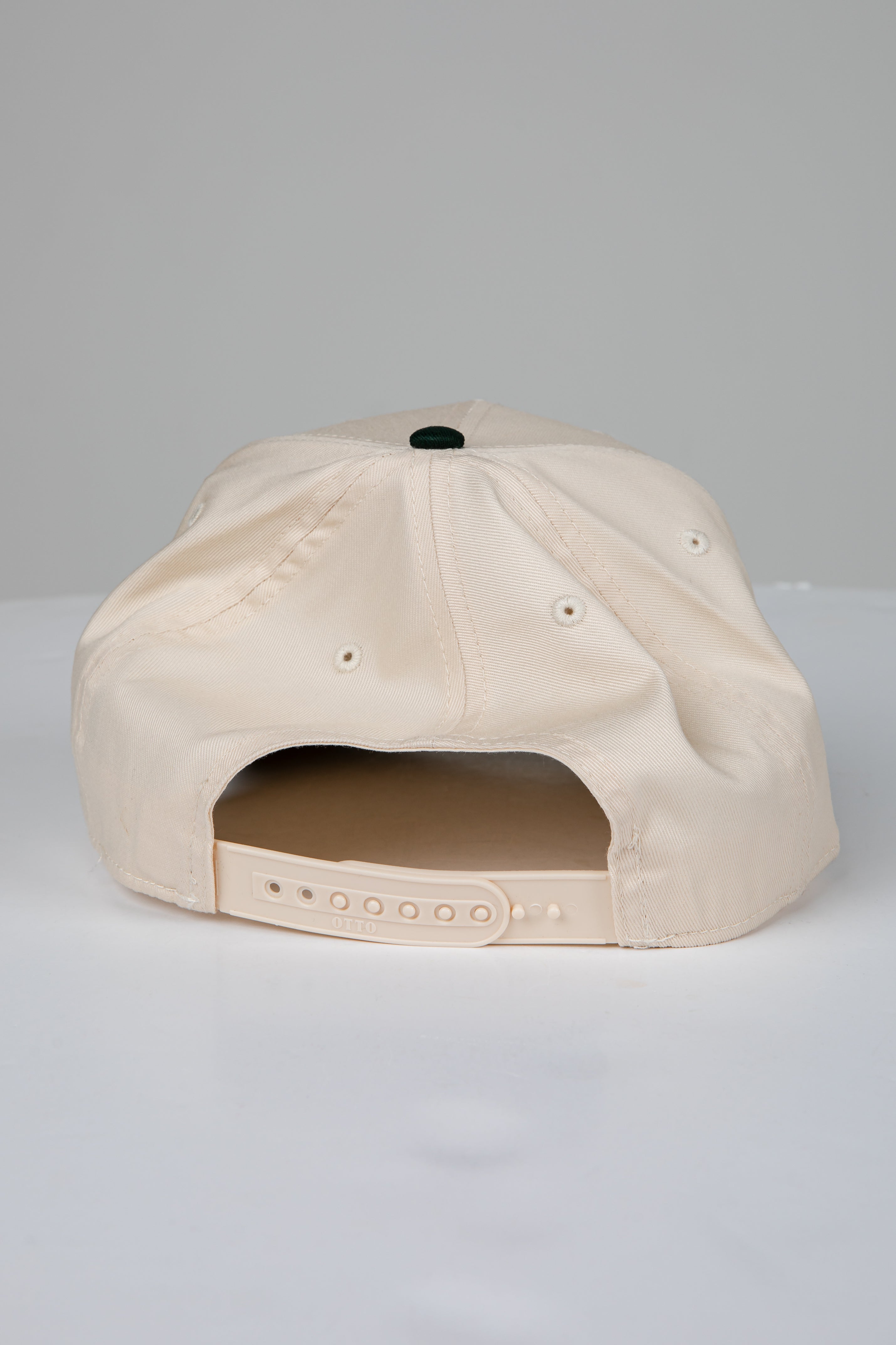 Beige cap with a black button on a light gray background