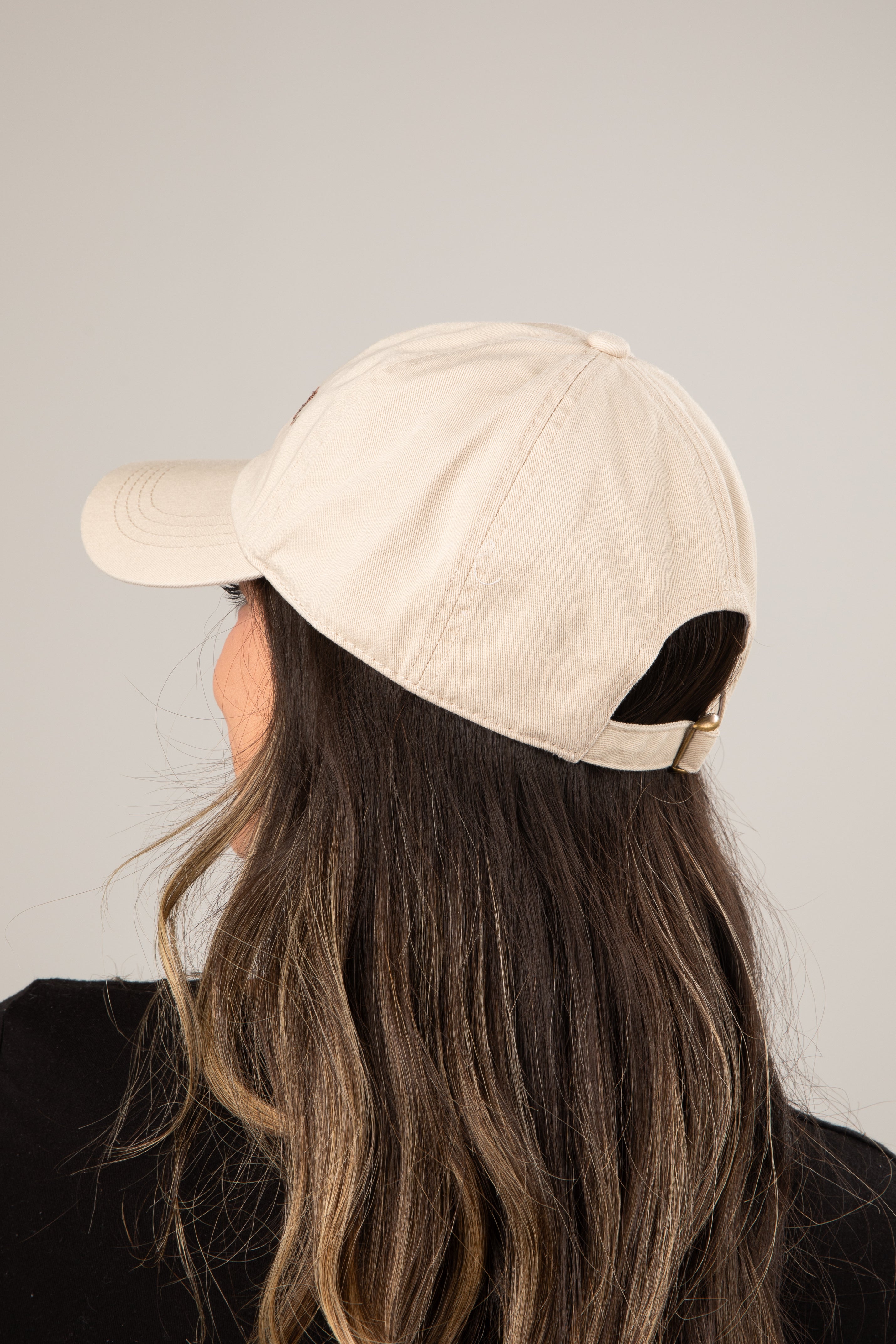 Person wearing a beige baseball cap on a plain background