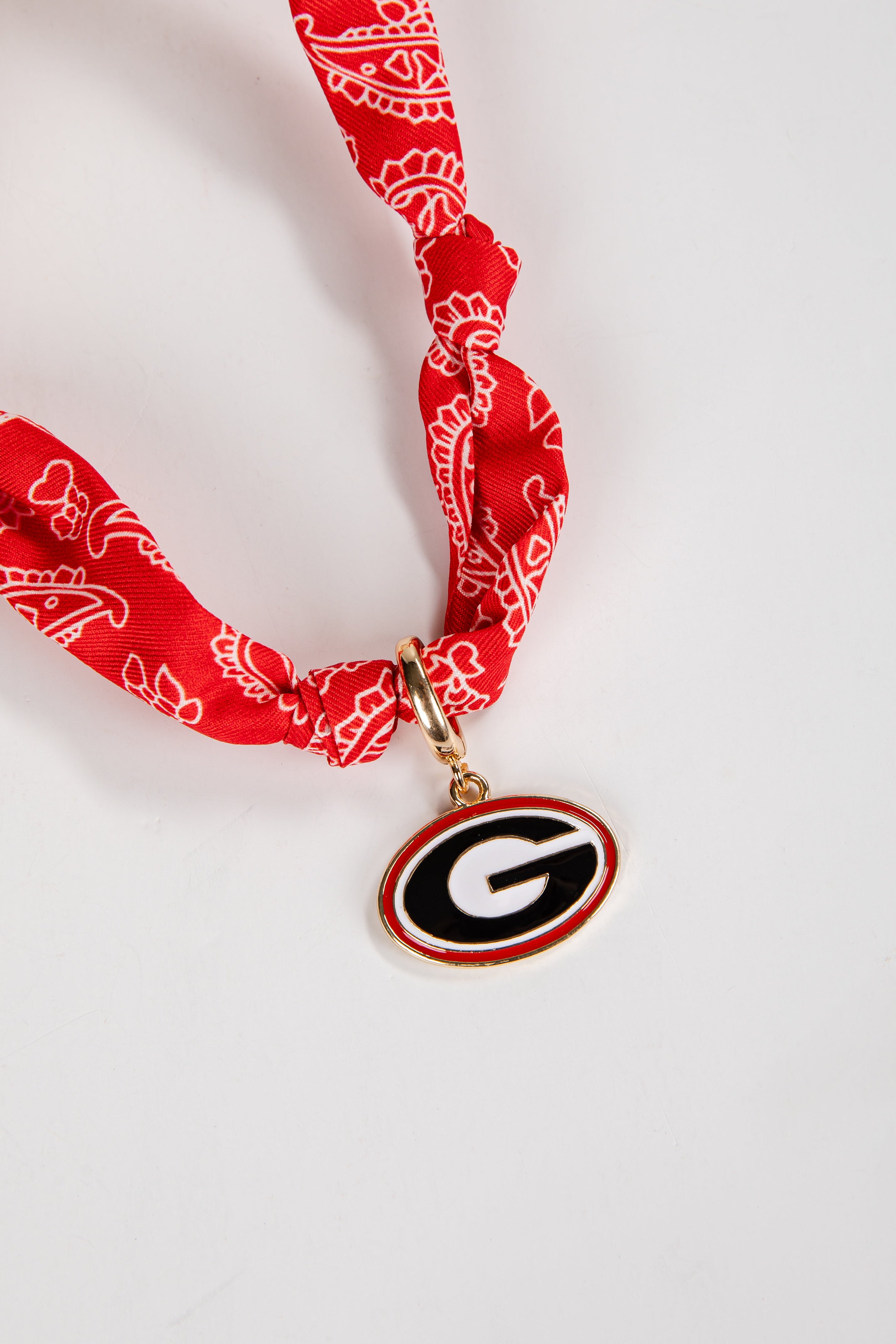 Red bandana with a gold clasp and a pendant on a white background