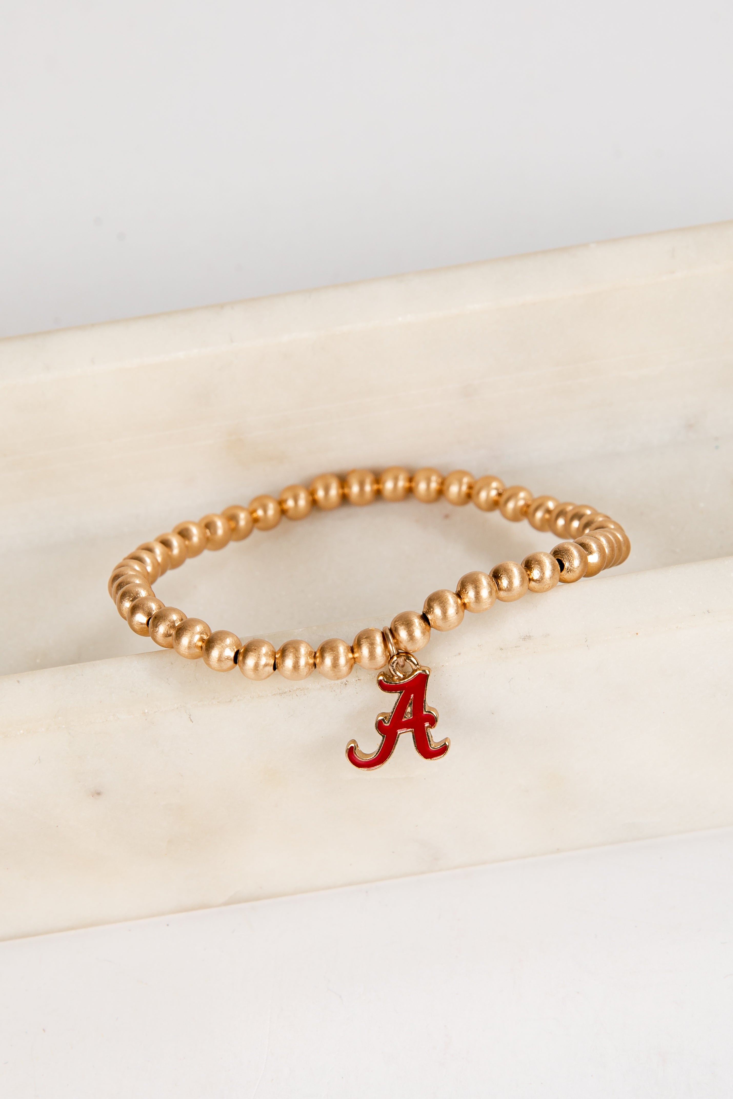 Gold beaded bracelet with a red &
