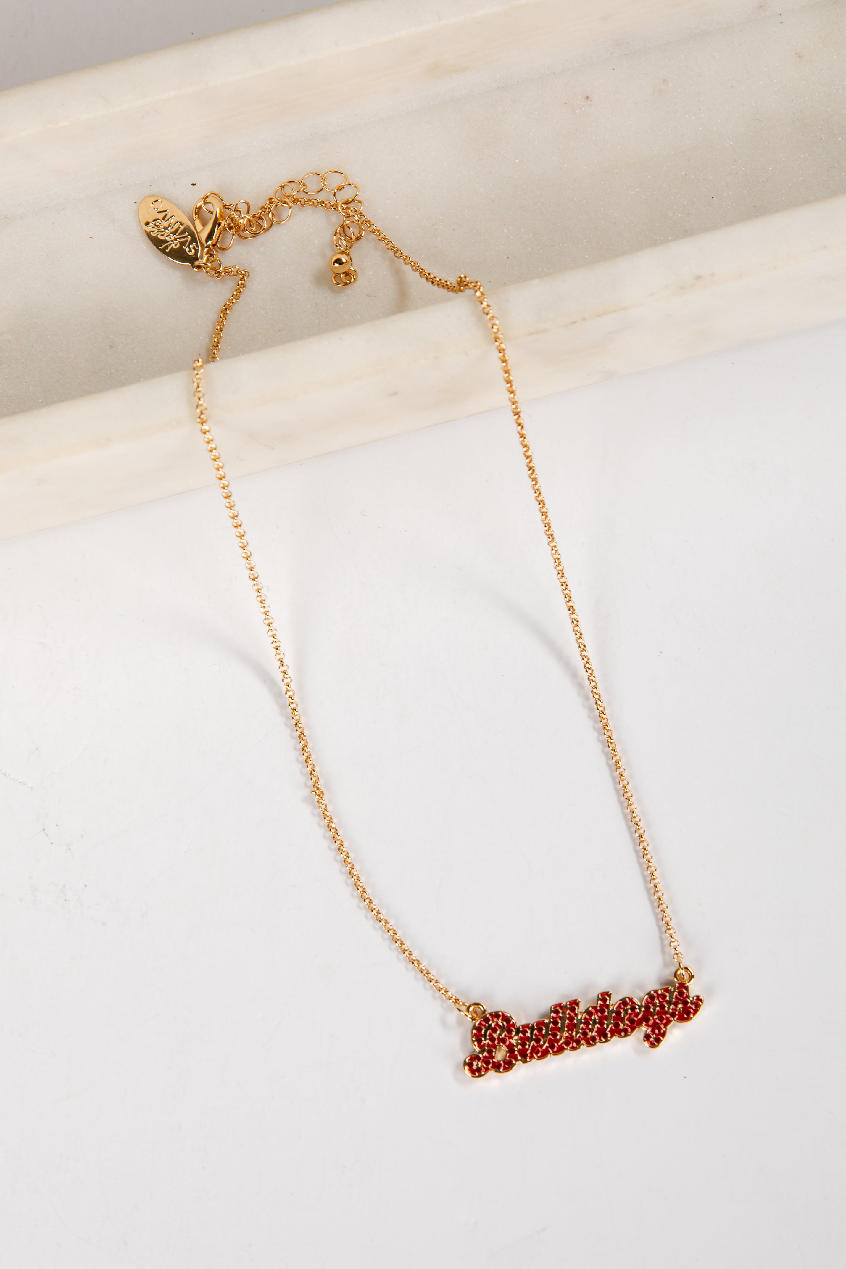 Gold necklace with red lettering on a white surface