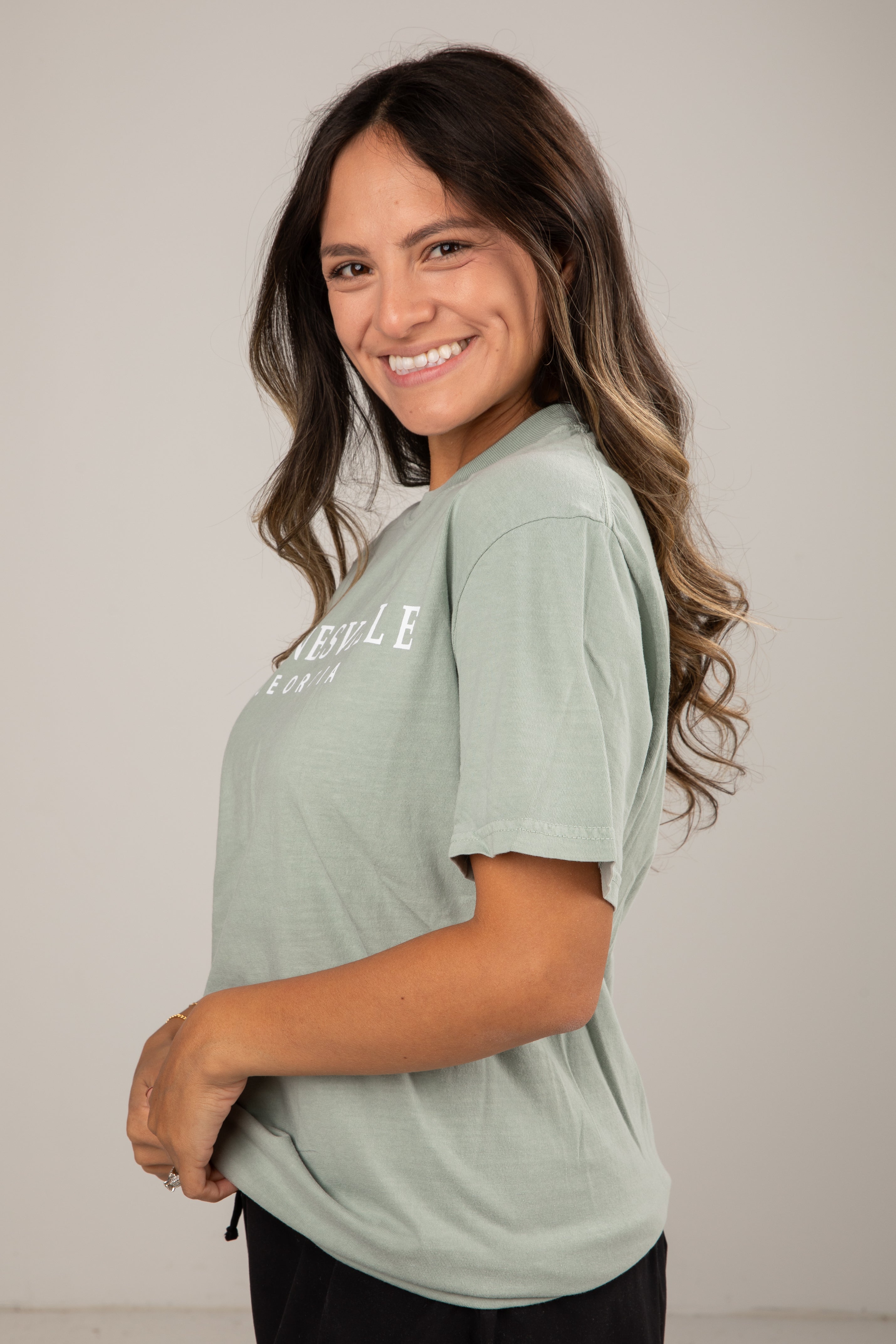 Woman wearing a light green t-shirt with text on a plain background