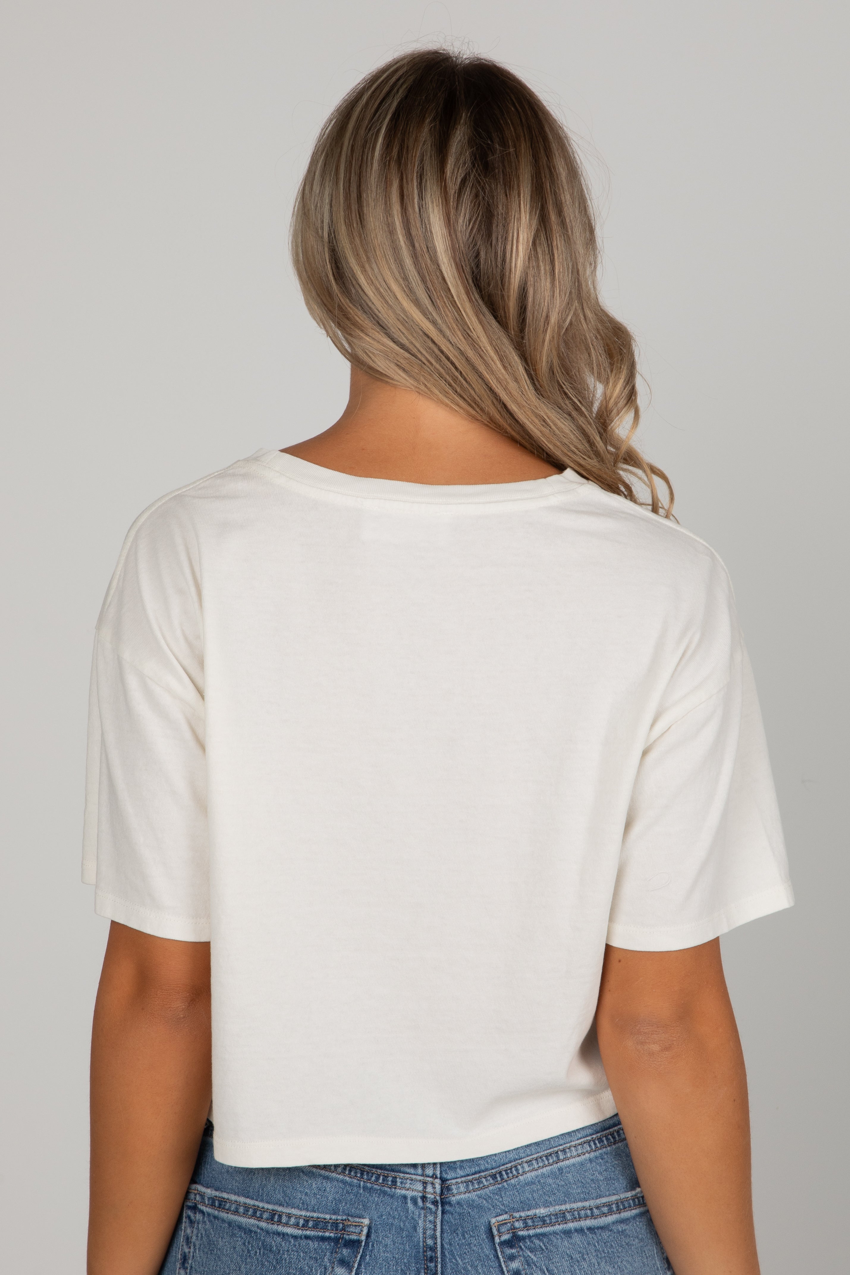 Person wearing a white t-shirt and blue jeans on a plain background