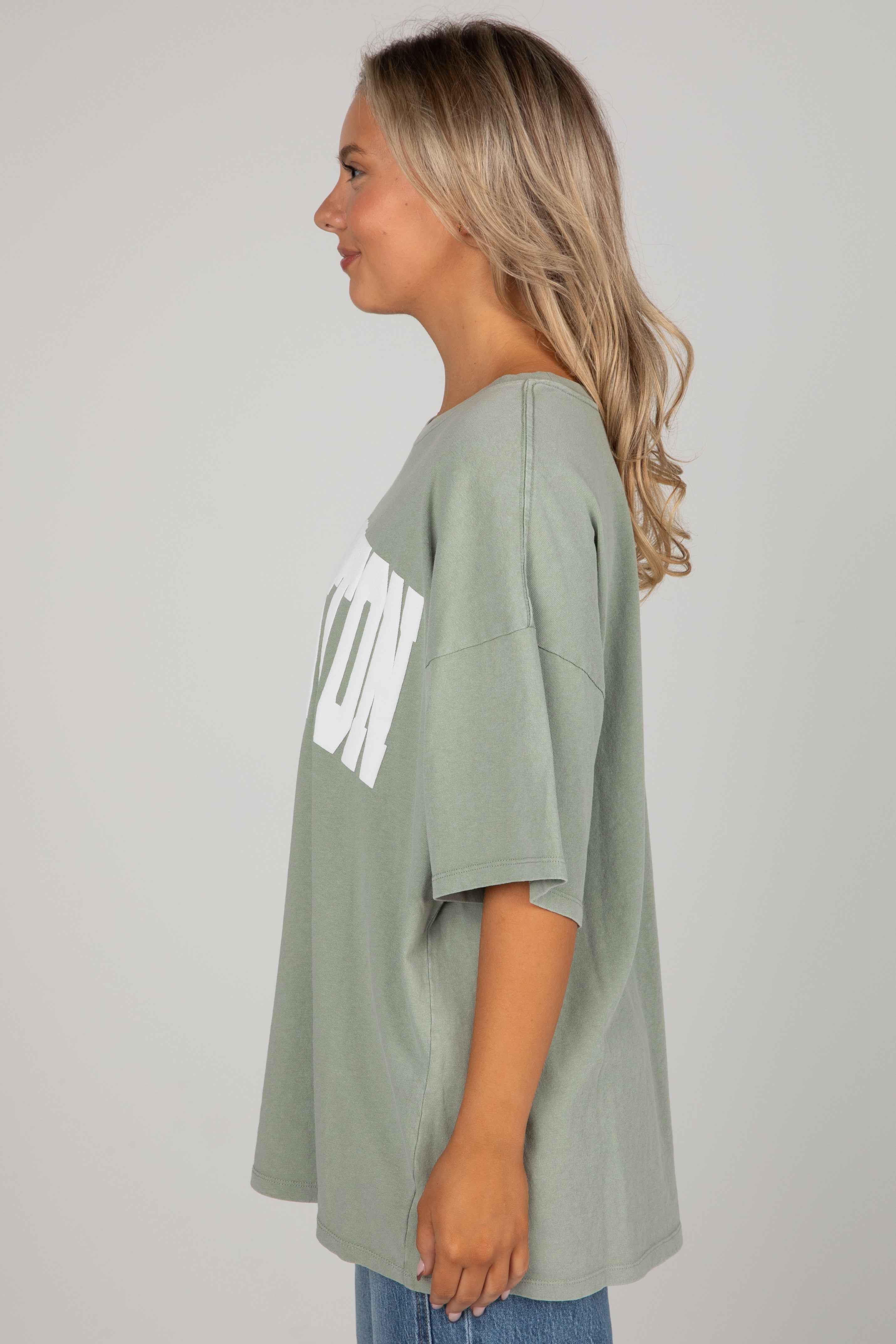Woman wearing a green oversized t-shirt with &