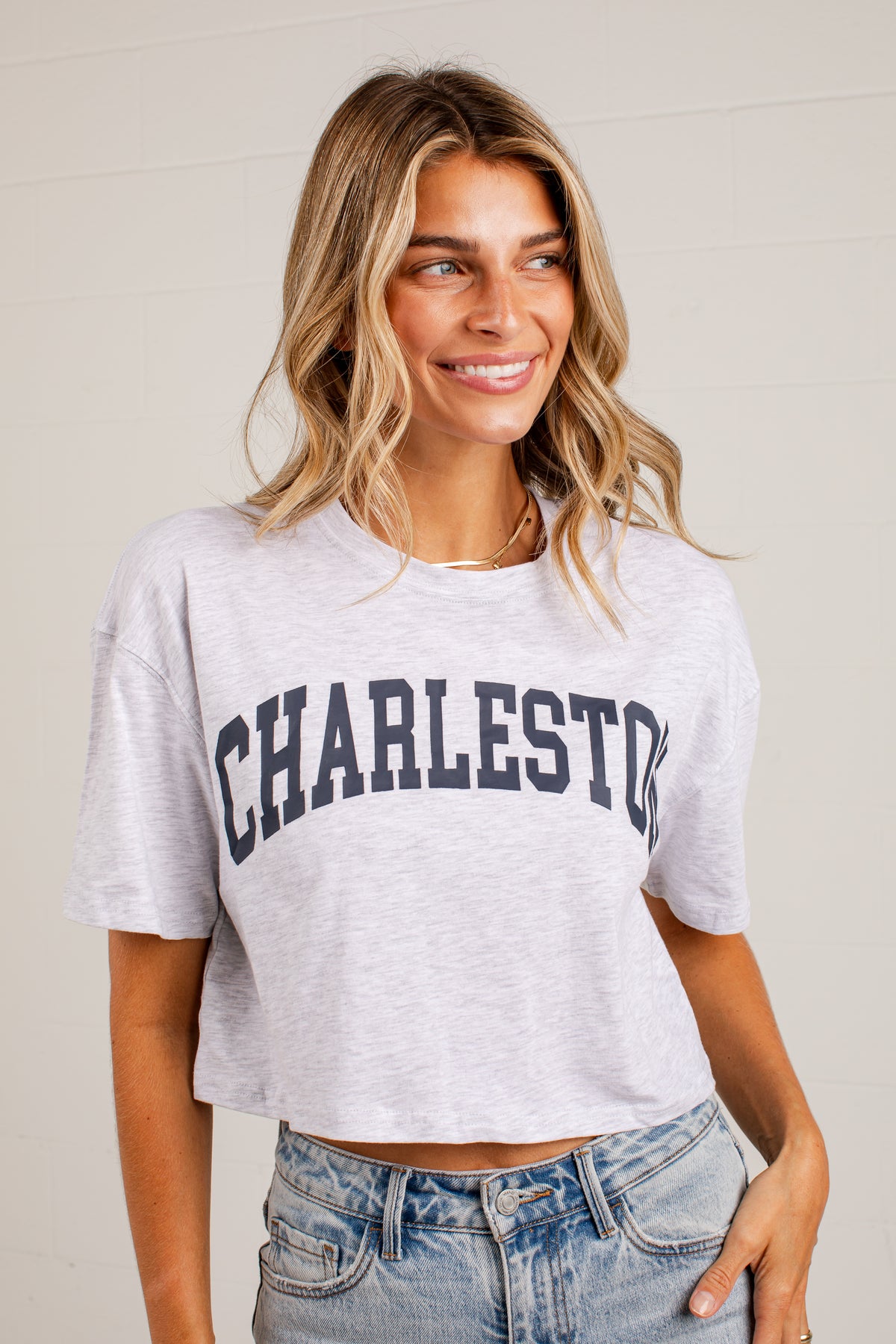 A woman wearing a light heather gray cropped t-shirt with &